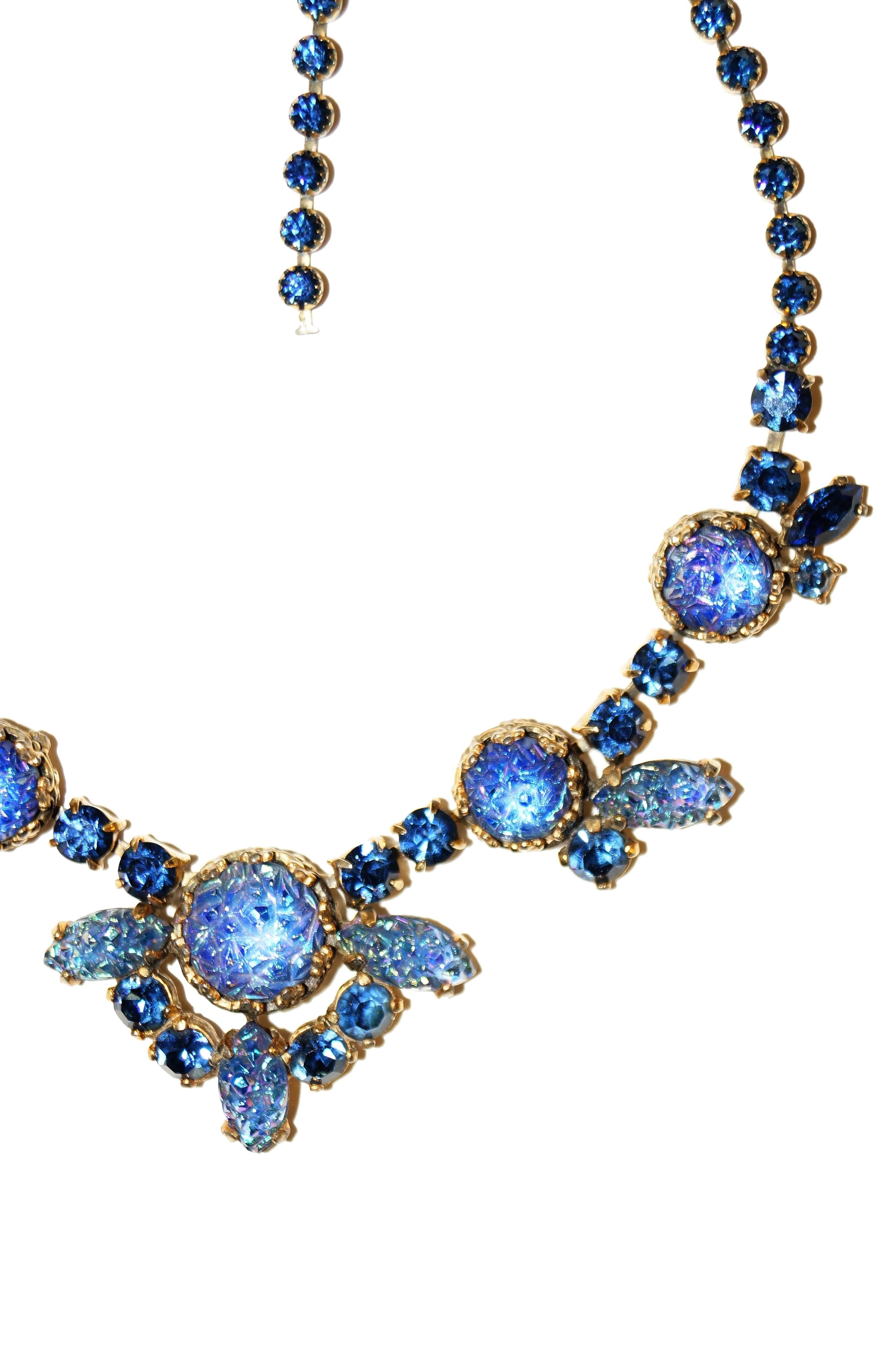 Beautiful vintage rhinestone and molded art glass necklace by Elsa Schiaparelli. The necklace features amazing iridescent icy blue “lava rock” cabochons and marquise cut and round multifaceted rhinestones. The piece has a large lava rock center