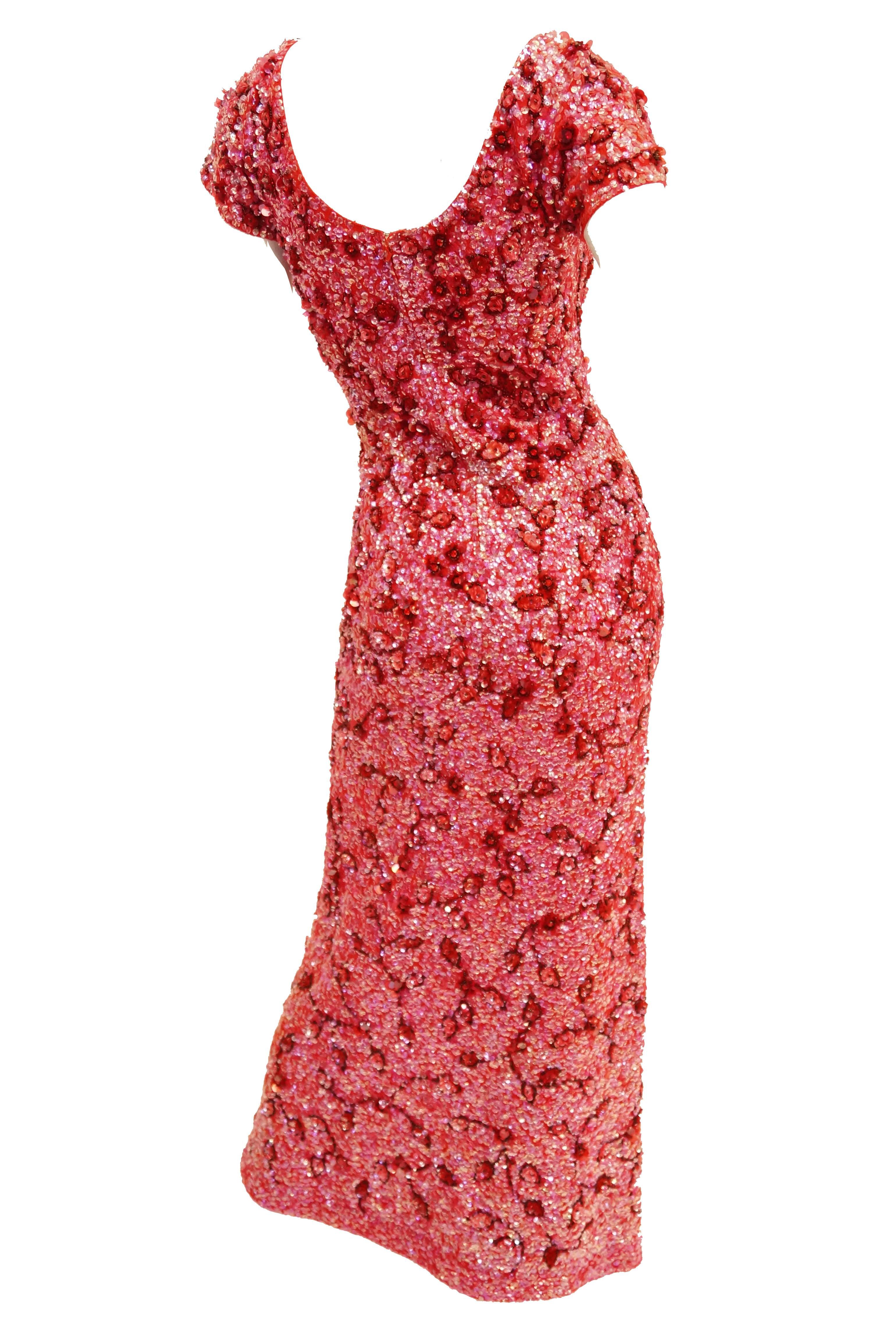 Resplendent curve - hugging sweater knit sequin dress. This mid century piece is maxi length, has short sleeves, a rounded collar, a medium scoop back, and a gently fluted skirt. The dress is fully sequined in playful red and pink iridescent floral