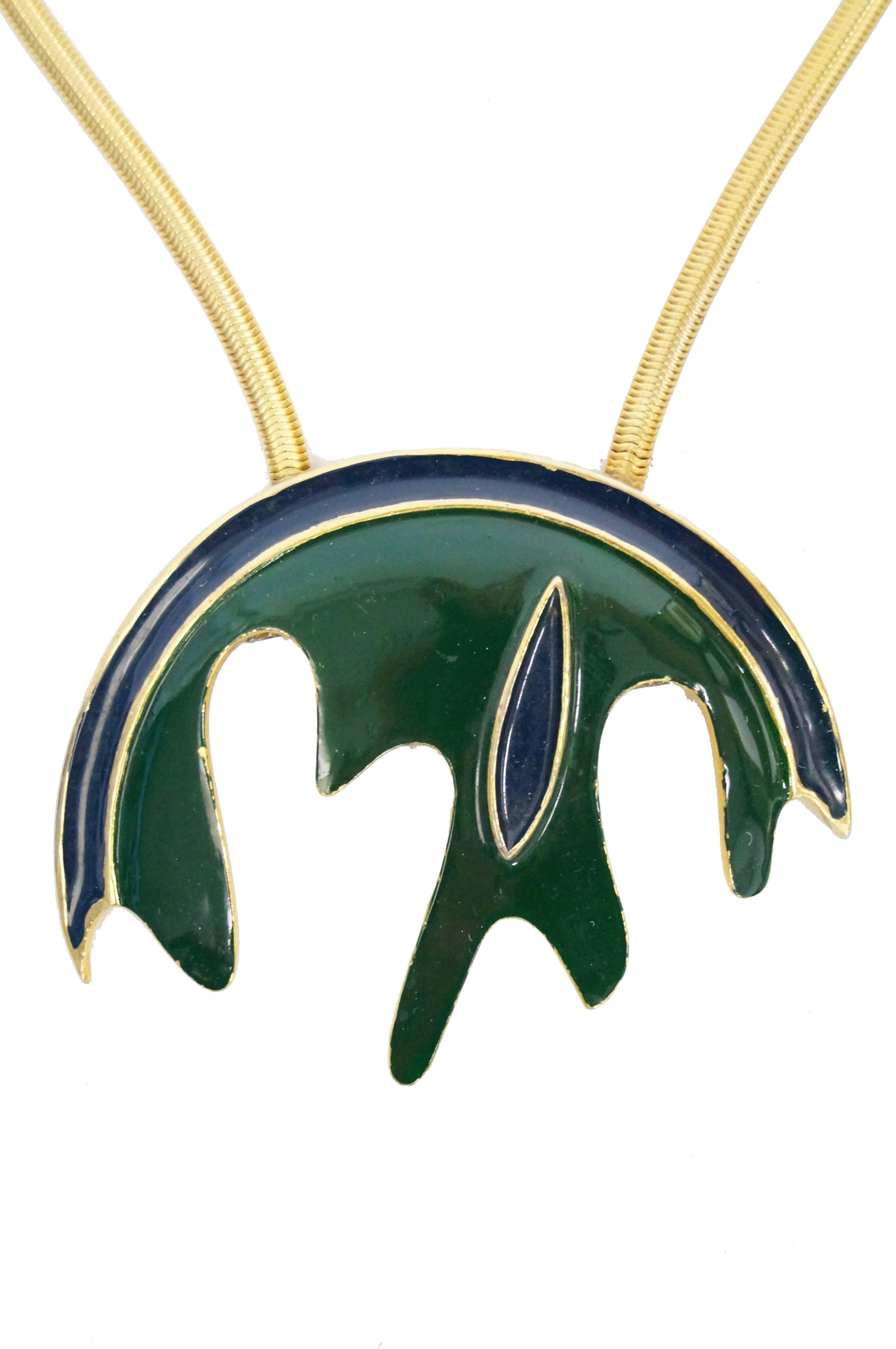 Brilliant modernist medallion necklace by Pierre Cardin. The necklace features an organic semi-circle of blue and green enamel suspended on a thick gold tone snake chain. The medallion pendant is composed of a green splash, making up the body of the