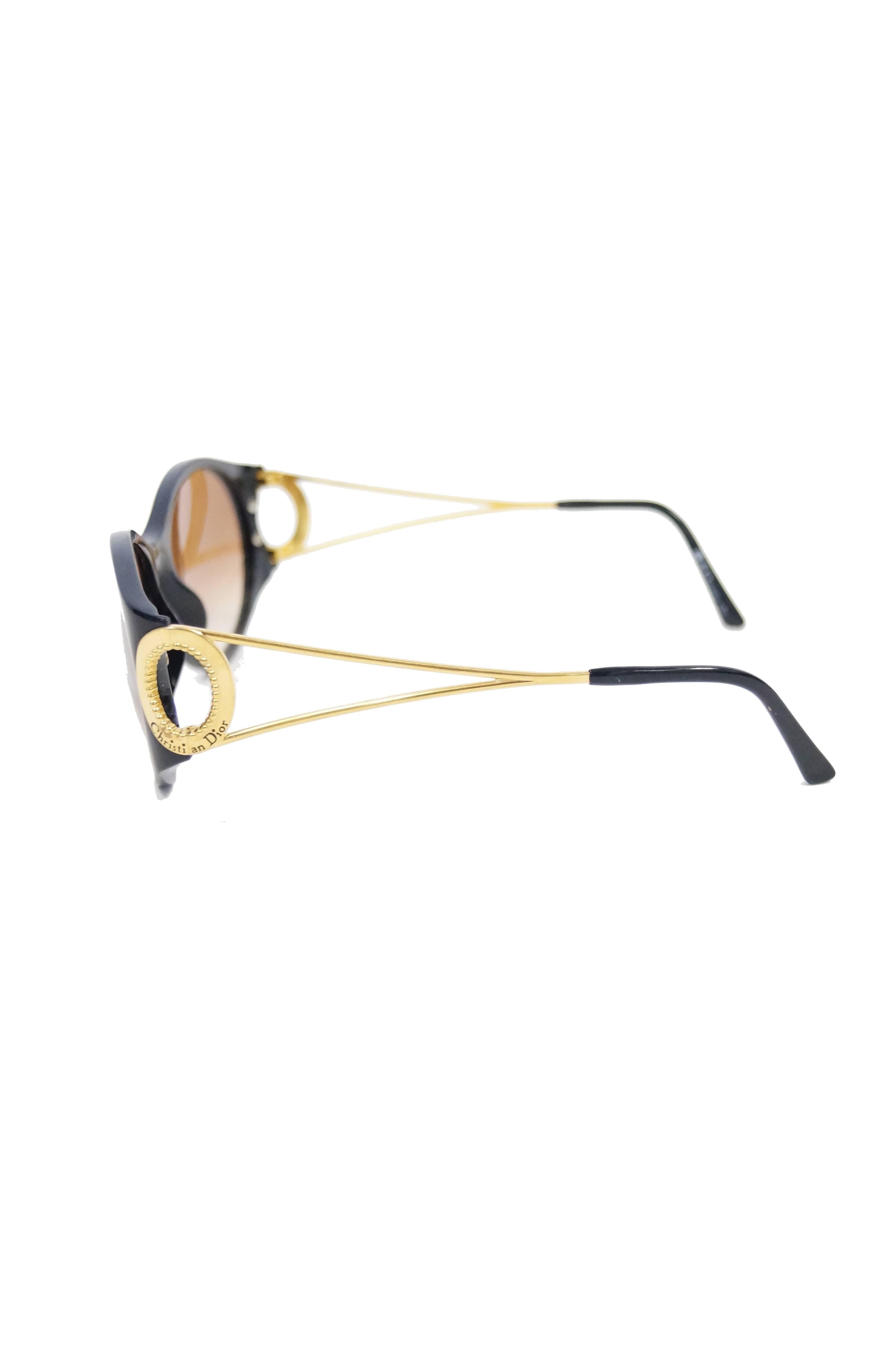 1980s Christian Dior 2661 Sunglasses. The glasses are composed of glossy black acrylic, with gold -tone, open - structure temples with black earpiece tips. The hinges of the glasses are gold - tone and circular, with 