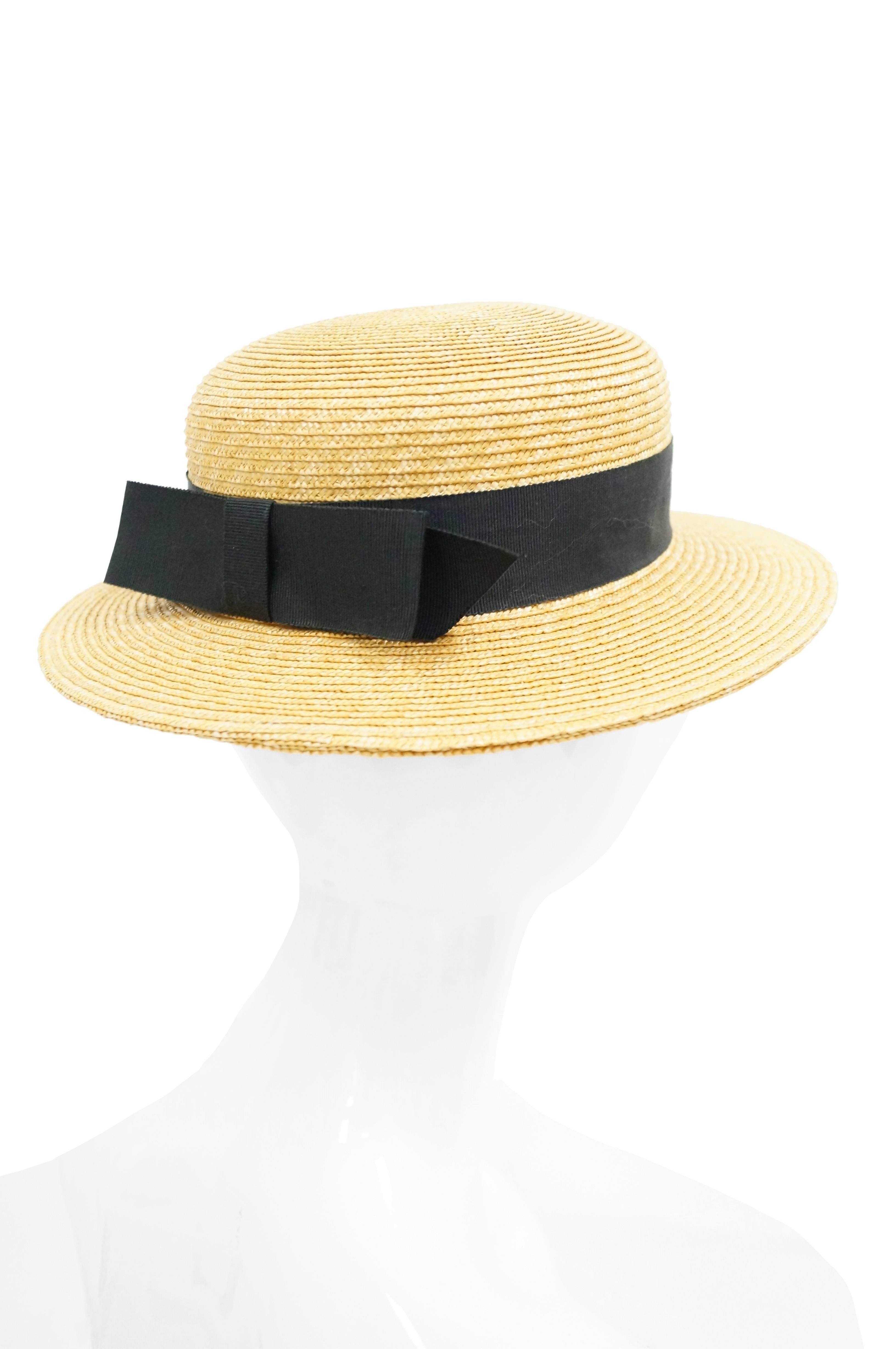 Stay cool in the heat with this vintage YSL hat! The straw hat features a medium - size flat brim and tall, rounded crown. The hat is reminiscent of a boater hat, with its wide black grosgrain ribbon, ending in a bow at the back. Interior of hat has