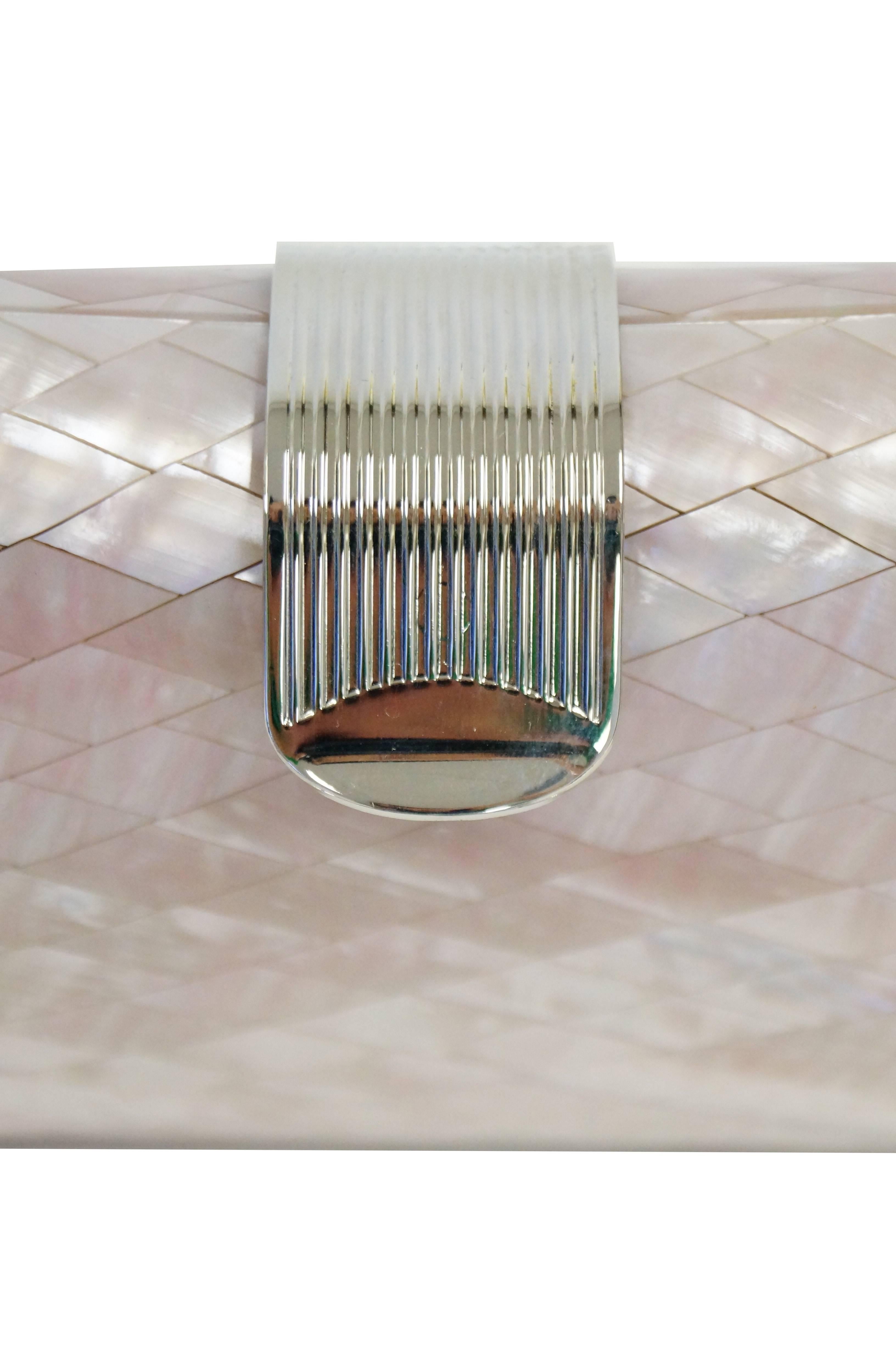 Beautiful iridescent pink evening clutch by Lisette. The clutch is rectangular with curved corners and rounded sides. The clutch is composed of shiny pink mother of pearl diamonds arranged in a grid, and covered in a layer of lucite. The top of the
