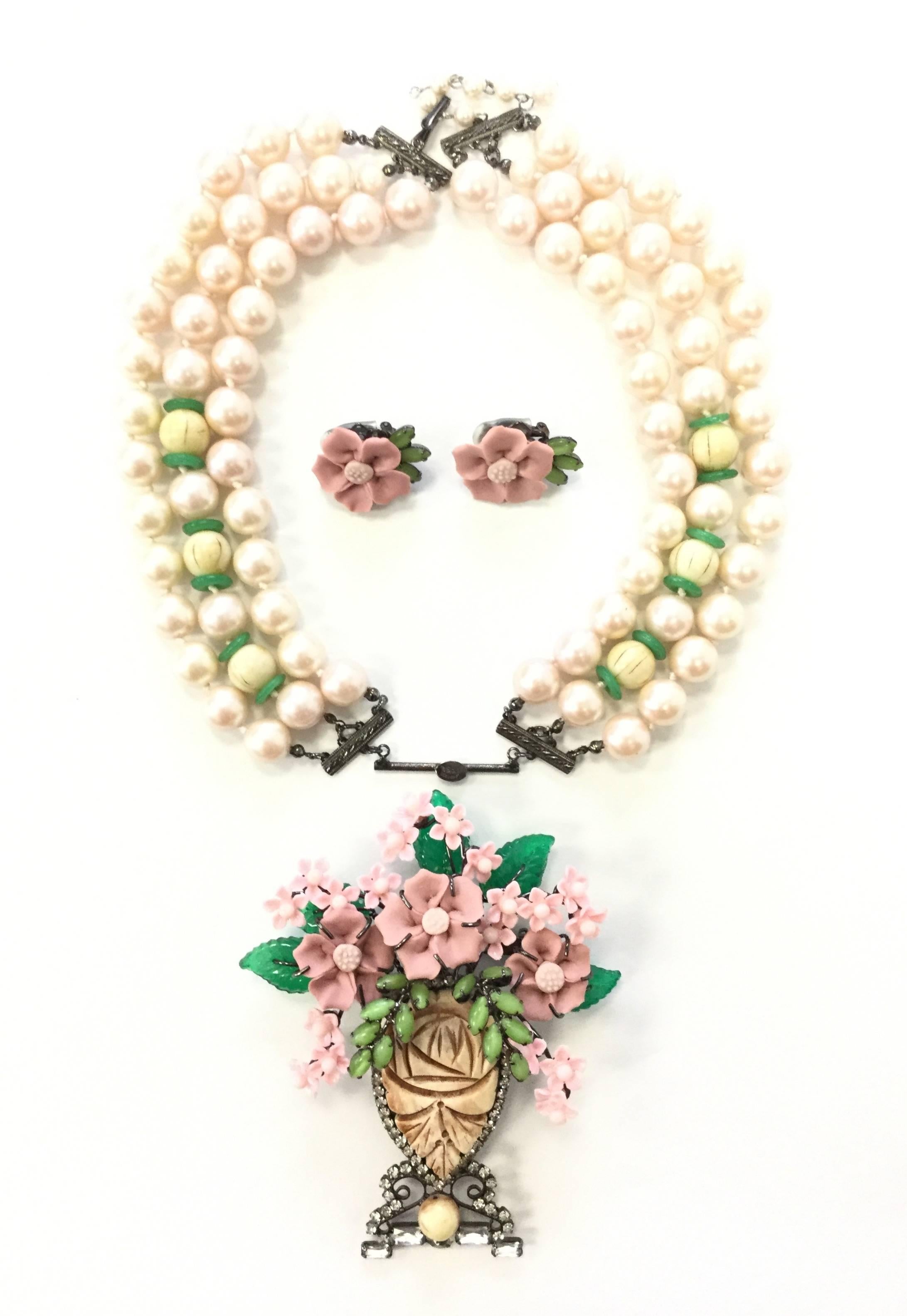 Fabulous Polynesian-inspired jewelry set by Larry Vrba! This set features a collar-length necklace composed of faux pearls and carved seed beads with green spacer beads. The necklace pendant is an impressive floral bouquet composed of glass