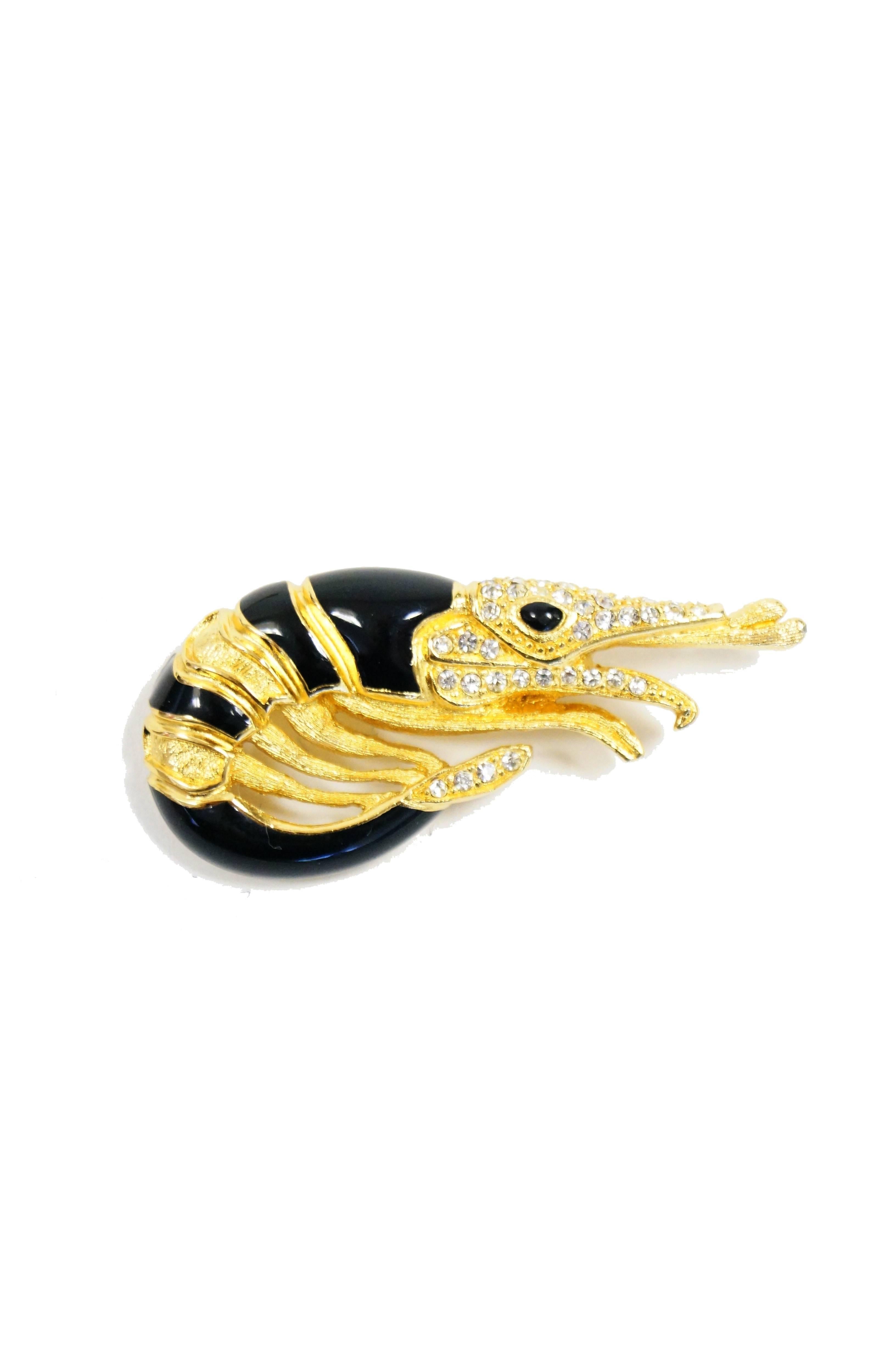 Whimsical black and gold tone Christian Dior shrimp brooch. The shrimp is primarily gold, with accent bands of black enamel. The shrimp's eye is a brilliant black enamel oval, and its rostrum and tail are accented with crystal pave rhinestones.