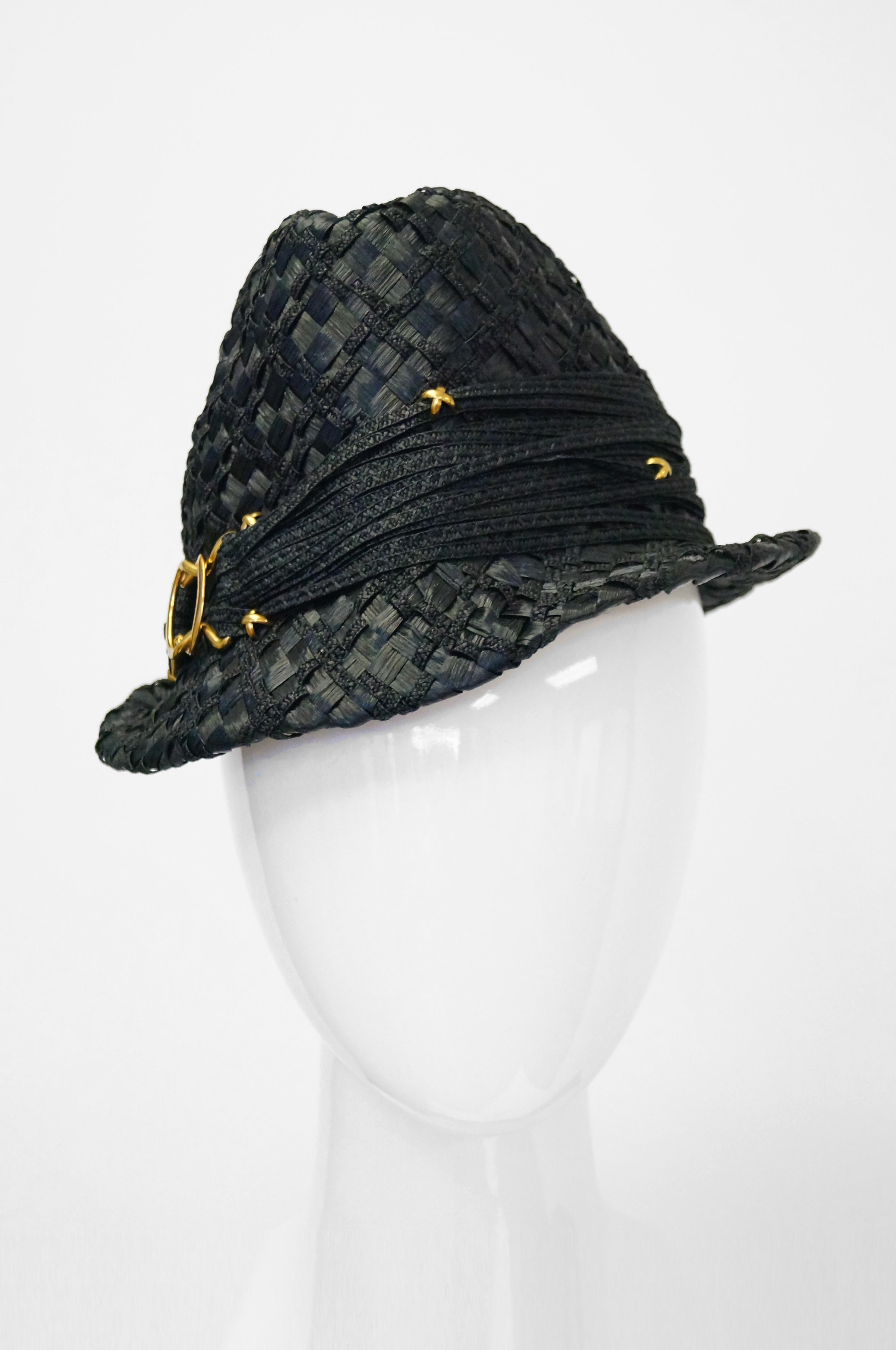 Fabulous black glossy woven raffia sun hat by YSL! This Yves Saint Laurent trilby features a medium brim, high crown, and band composed of multiple strands of braided rope, accented by a circular gold tone buckle. 

24 Inch circumference