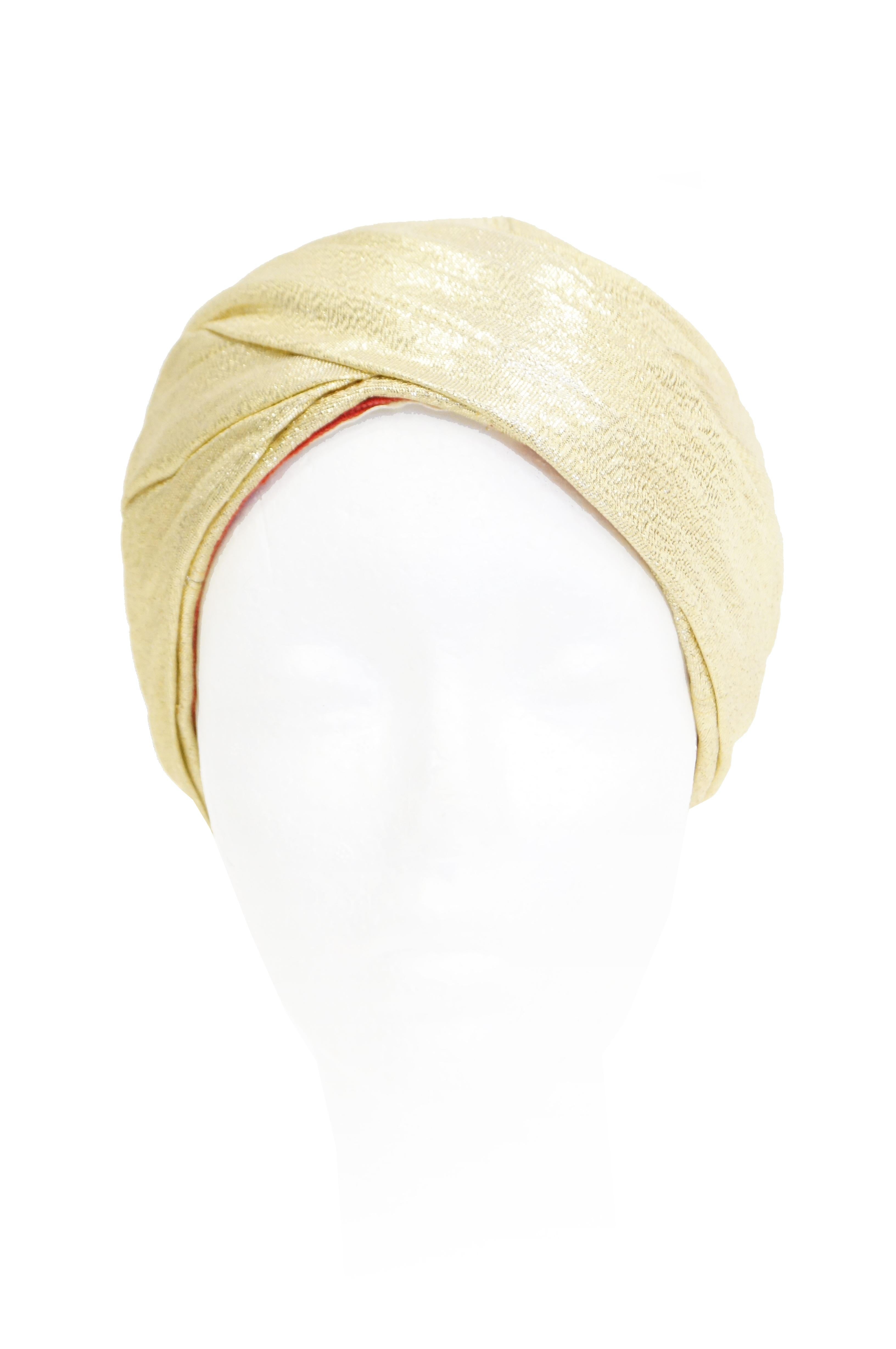 Extremely Rare Gold fabric pleated turban by Avant Garde designer Pierre Cardin.  Extremely well designed and constructed.  Turban can be worn high on the head or pulled down covering the crown. The turban is lined with red fabric and gross grain