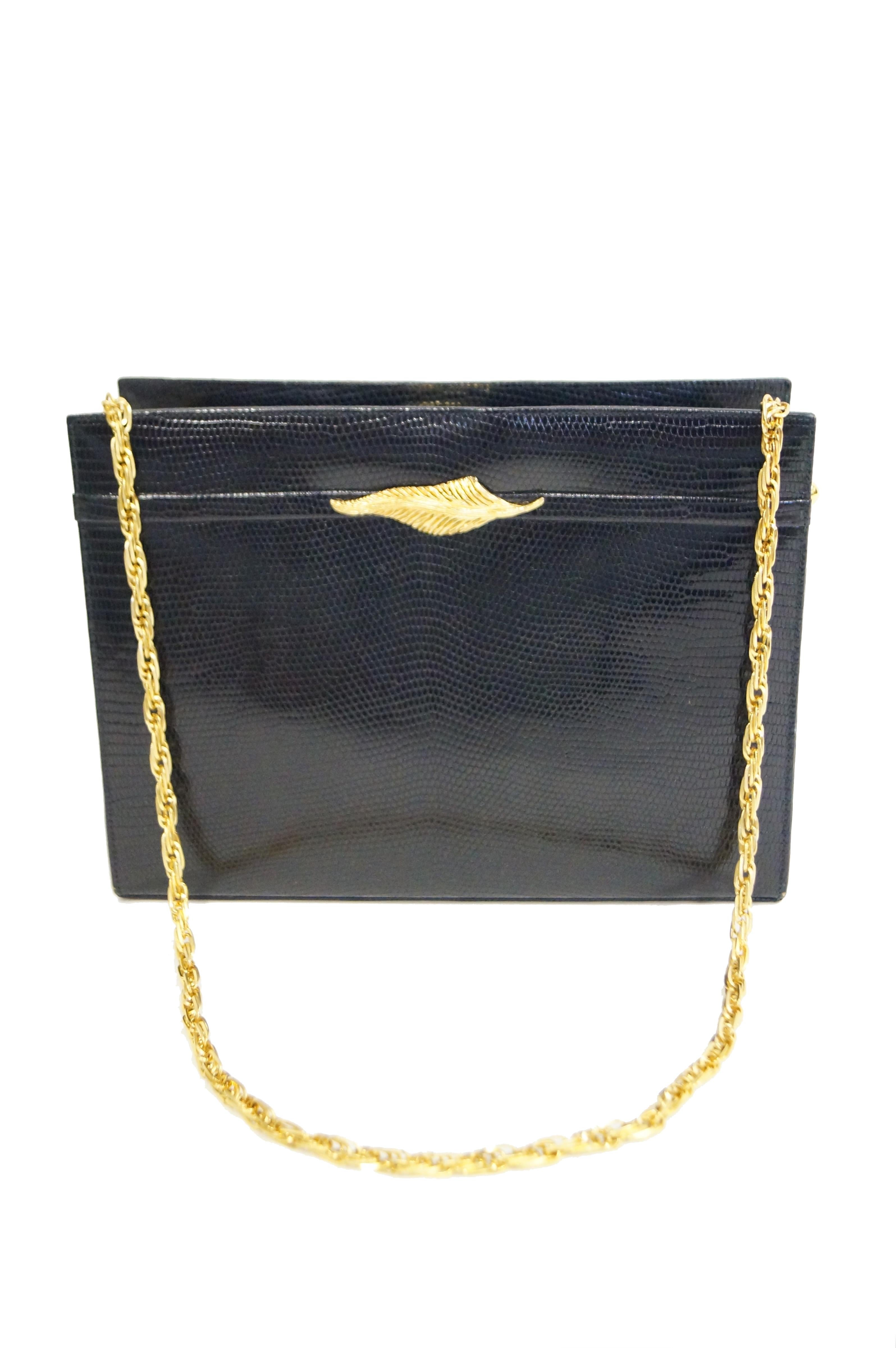 Black lizard hand bag with golden leaf detail on front. Sturdy leather construction with three compartments and zippered pocket.  Gold twist chain attached by gold knob hardware. Chain shoulder strap can be tucked into outer compartment as used as a