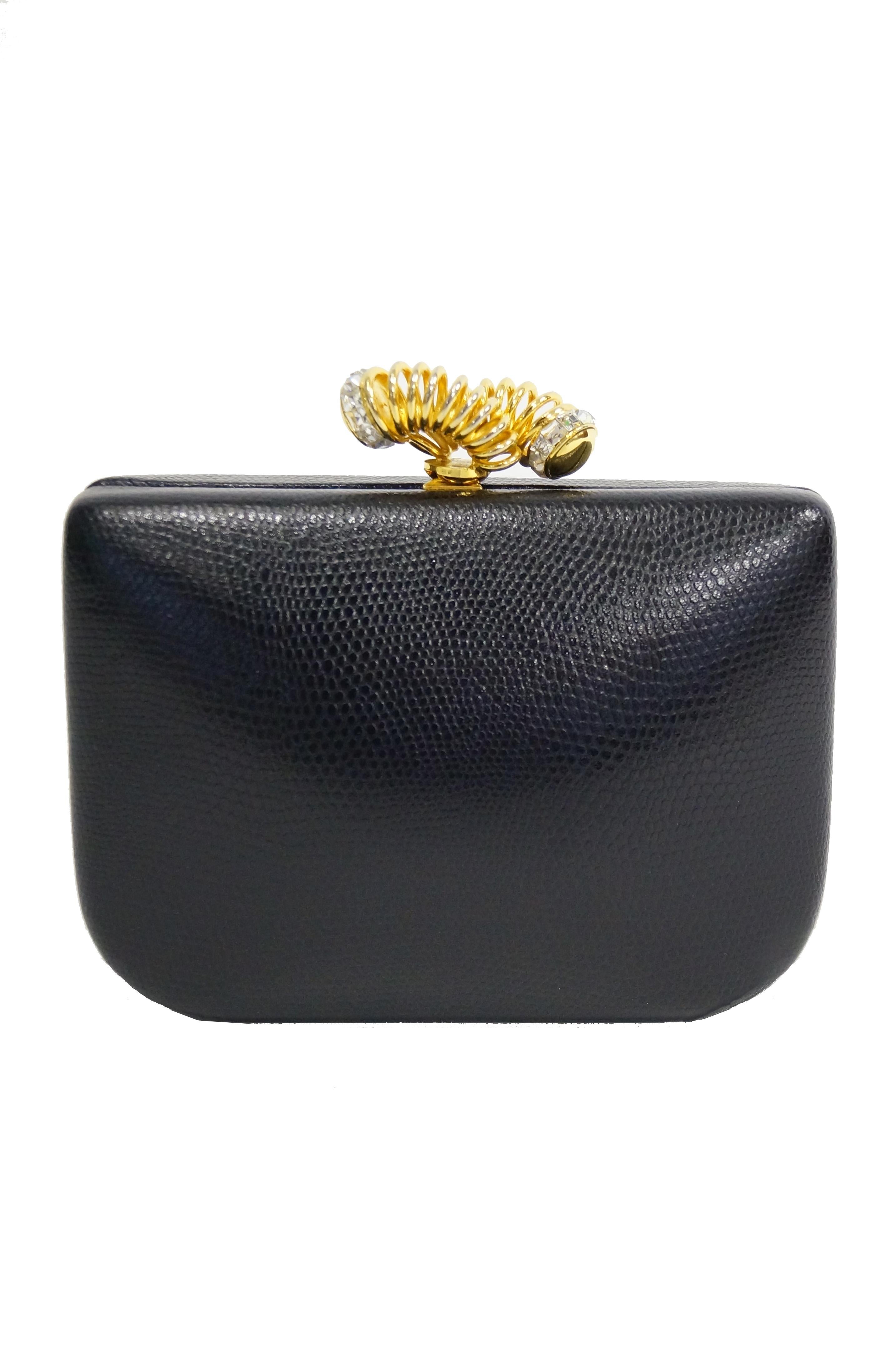 Amazing leather clutch by Rodo! The handbag features a rectangular, rounded edge body with black lizard skin leather body. The fantastic modernist gold tone and rhinestone spring swirl clasp gives way to a surprisingly spacious lined interior,