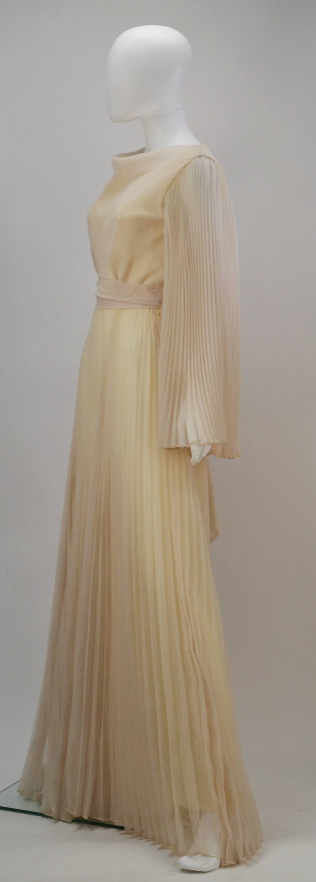 Let loose and dance around in this ethereal Mollie Parnis Boutique pleated dress. It features a subtle cowl or draped neckline and flowy pleated sleeves and skirt. It also includes a sash which ties delicately at the waist. Zipper center