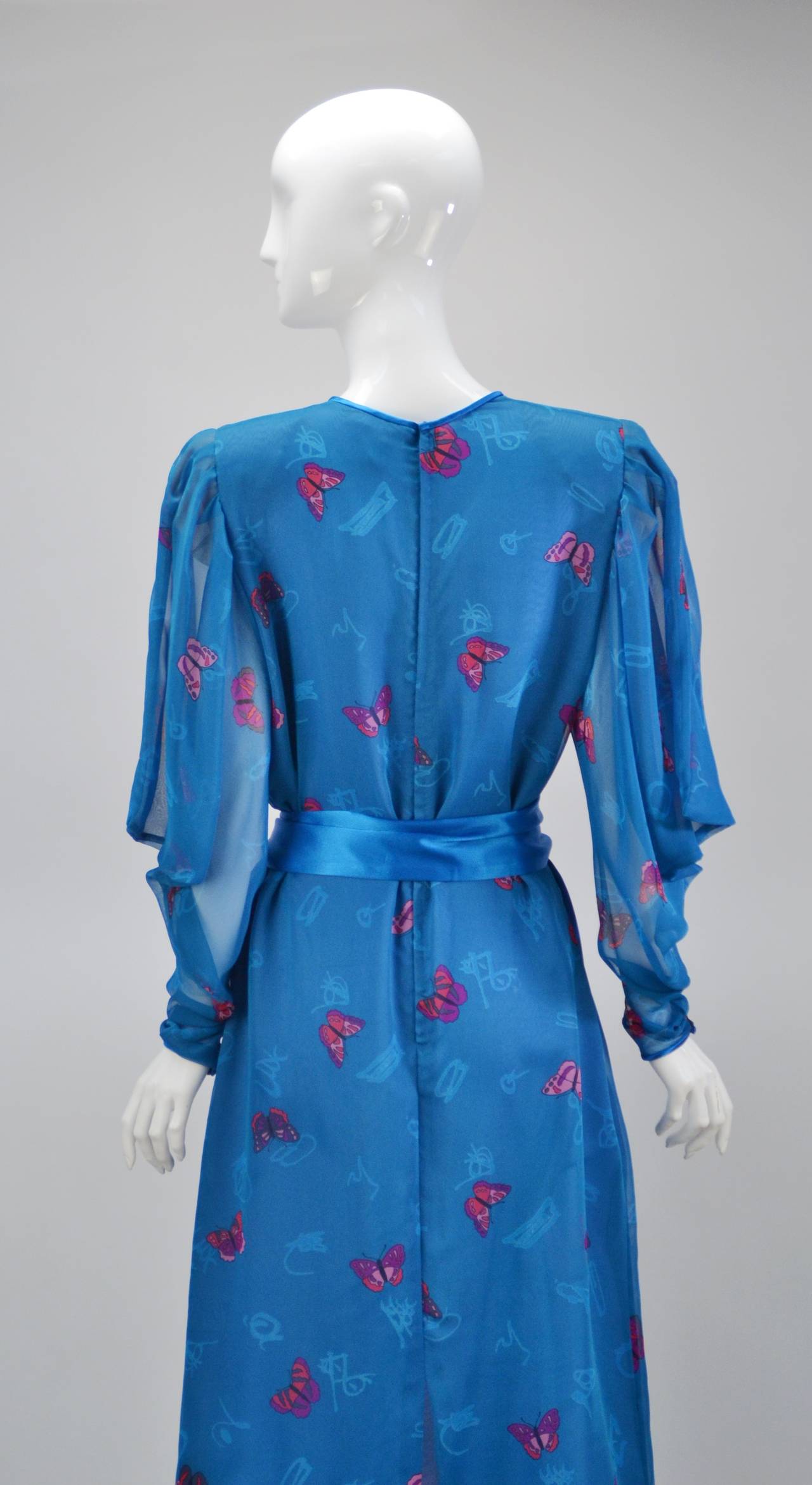 Classic chiffon day to evening dress by Hanae Mori will be worn with both elegance and comfort.  Beautiful blue with her signature butterfly throughout adds whimsy to your day. Dramatically draped sleeves are sheer with satin piping and snap