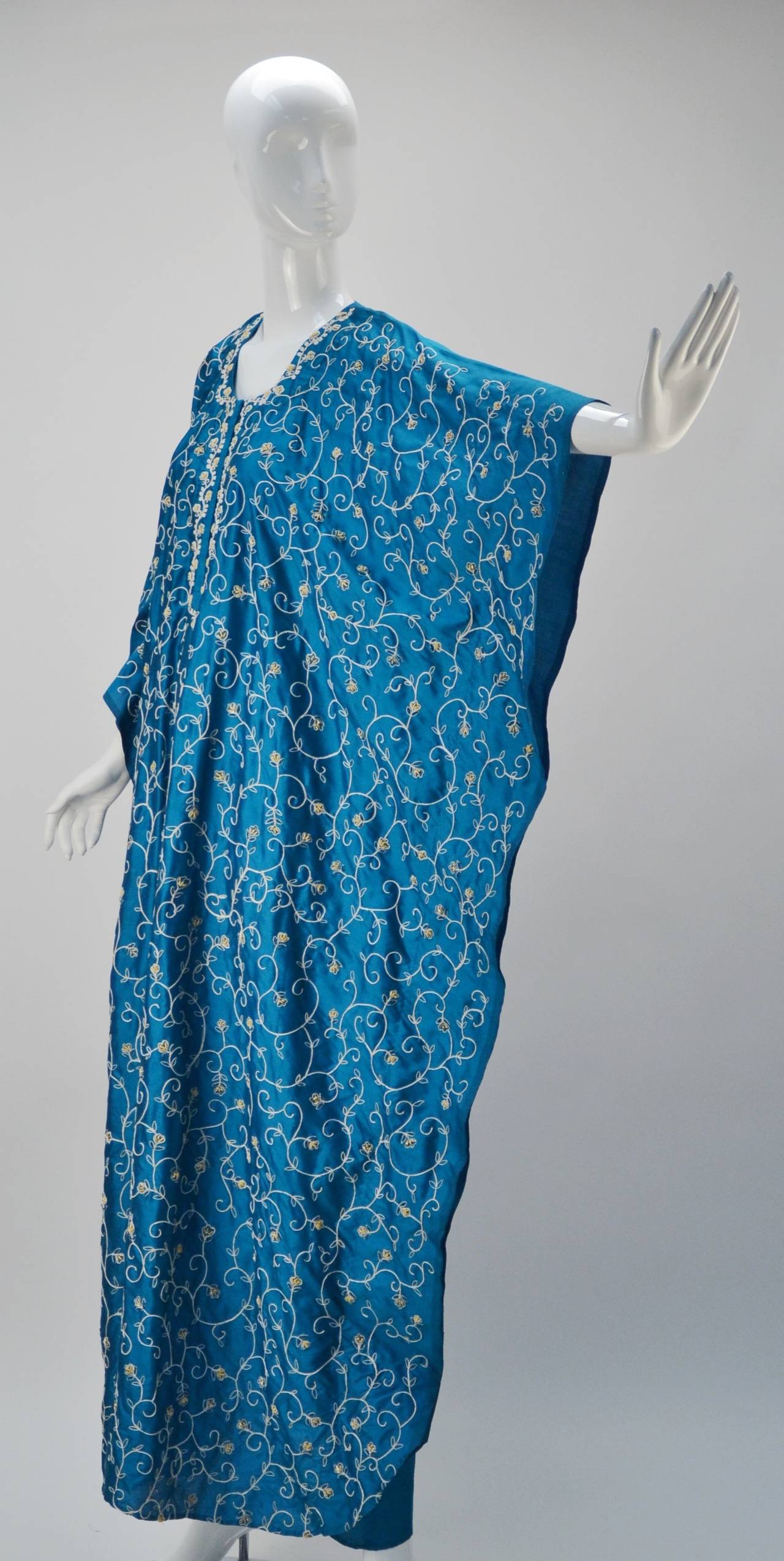 Exquisite blue silk floral embroidered caftan that was made at the exclusive Burlington's Taj Mahal Hotel Bombay. The embroidered and beaded detail are only on the front, whereas the back of the kaftan is solid silk. It has a center front placket