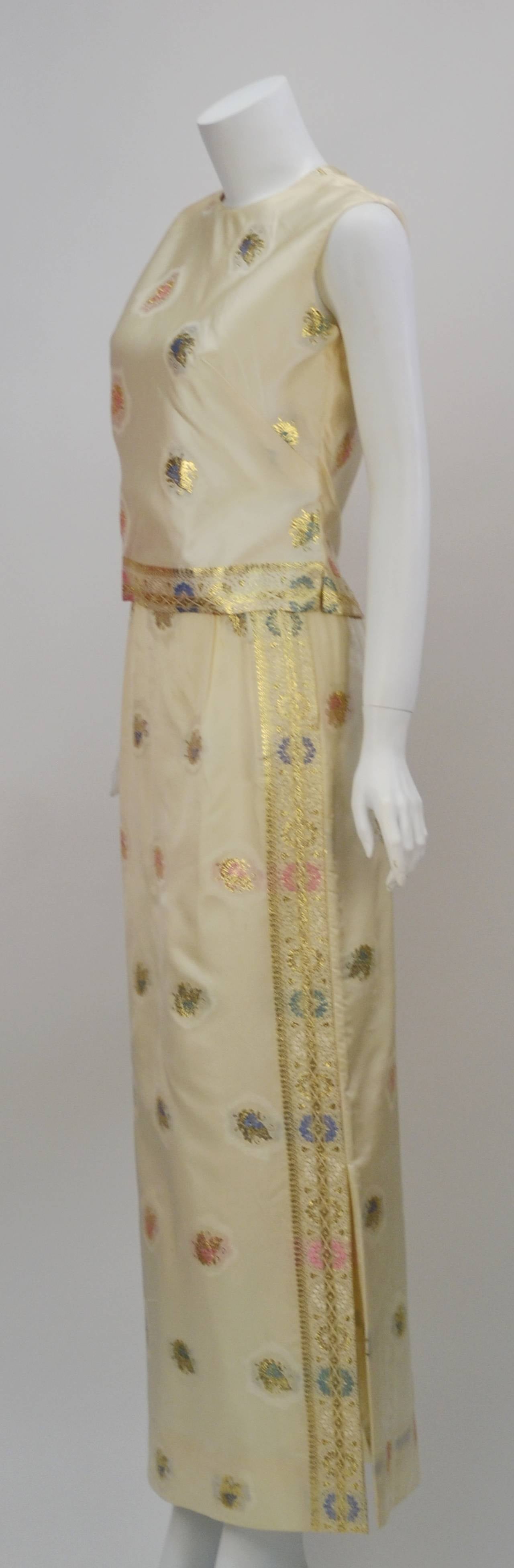 This 1960's sleeveless Asian inspired ensemble is perfect for any luncheon or can be worn at evening!  The item's fabric content is not listed but appears to be silk.  The ensemble boasts a colorful floral motif with woven gold metallic threads atop