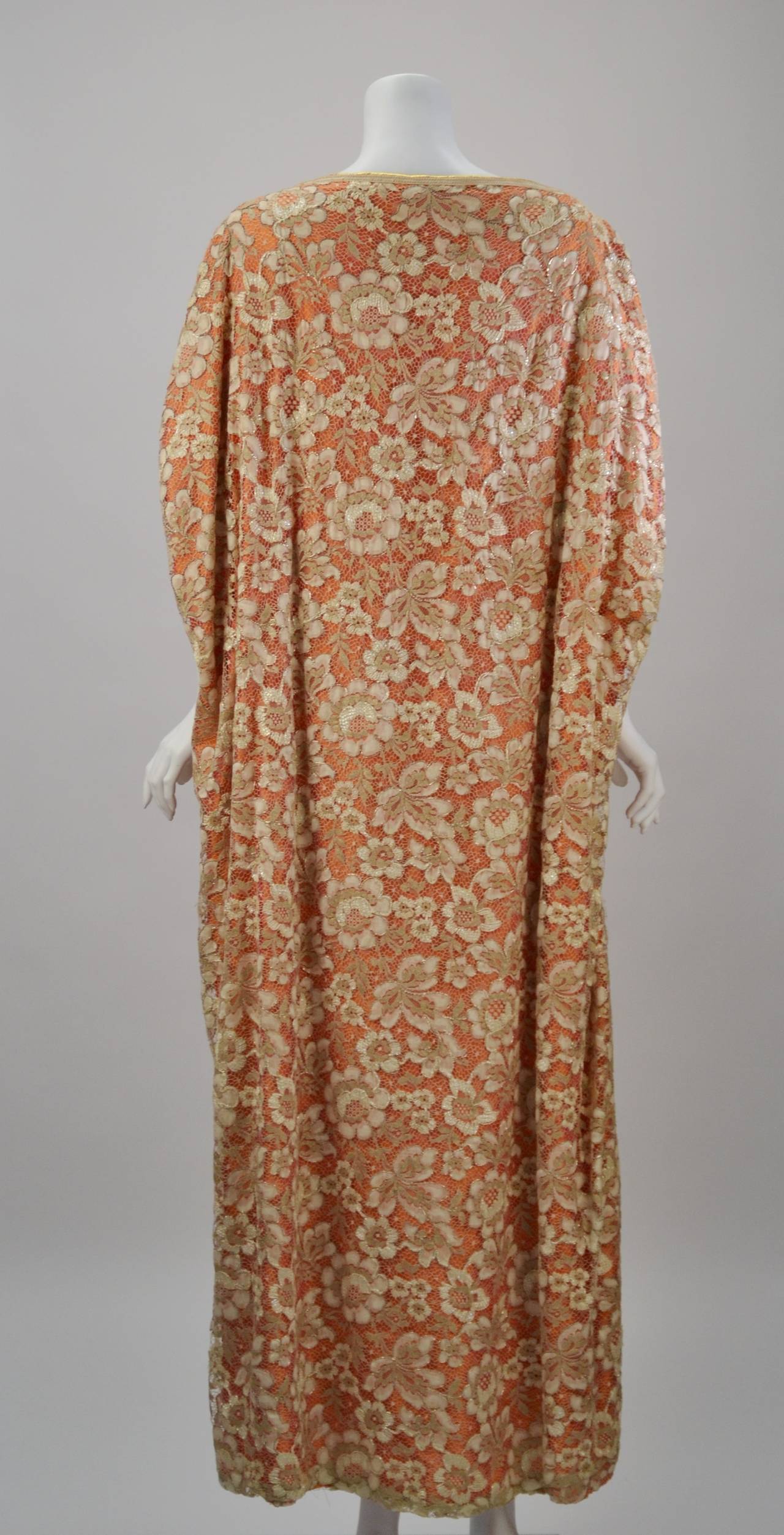 Extravagant late 70's Neiman Marcus coral raw silk with off-white lace overlay caftan gown. The gown features dolman sleeves, sashes that tie in front to create a waist and a cape-like silhouette in back. Intricate gold threading/trim is throughout