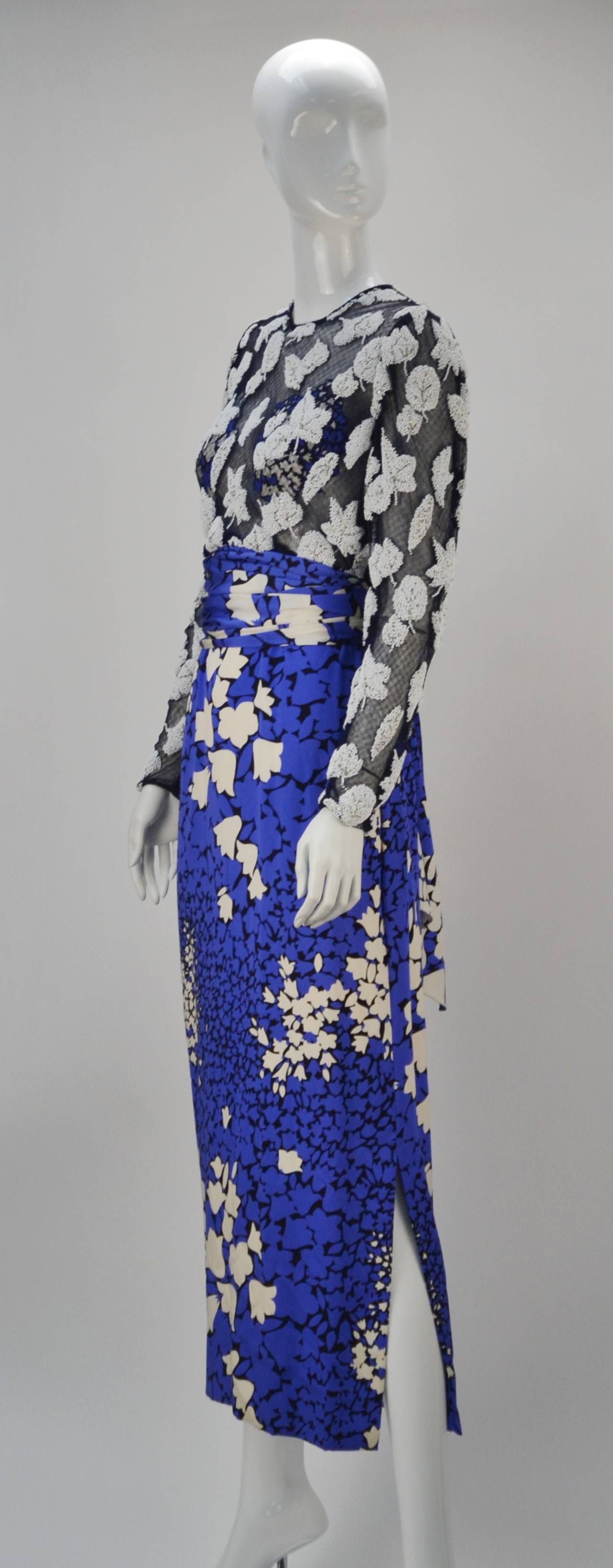 Beautiful multi-color blue, black and white silk dress with net and beaded long-sleeve bodice. There is a wide sash that ties at the waist. The bodice is sheer, however the bust area is lined. The dress fastens with a back zippered and hook-n-eye