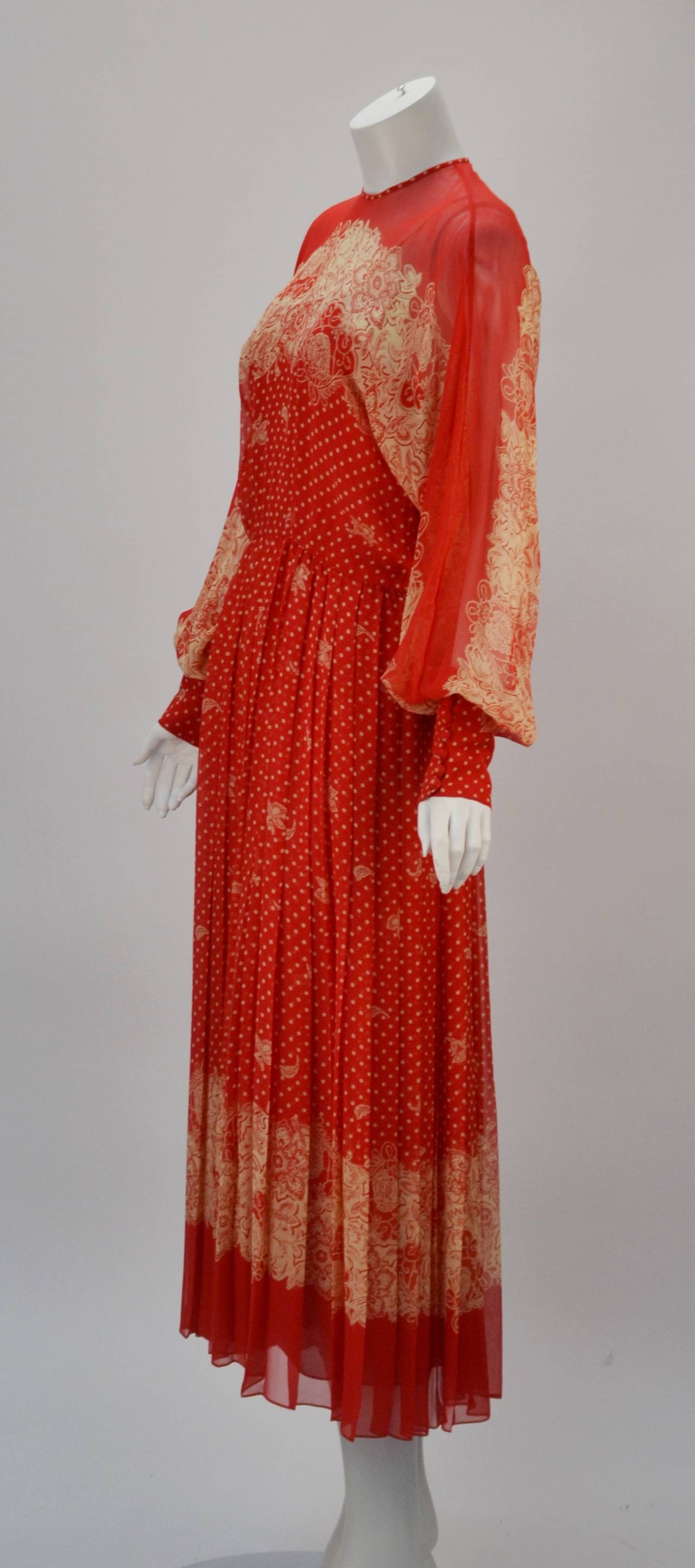 1980's silk Adele Simpson red with beige polka dot and floral print long sleeve dress. The dress appears sheer, but also has an attached slip, which is also sheer in its own right. The dolman sleeves have wide cuffs that fasten with fabric covered
