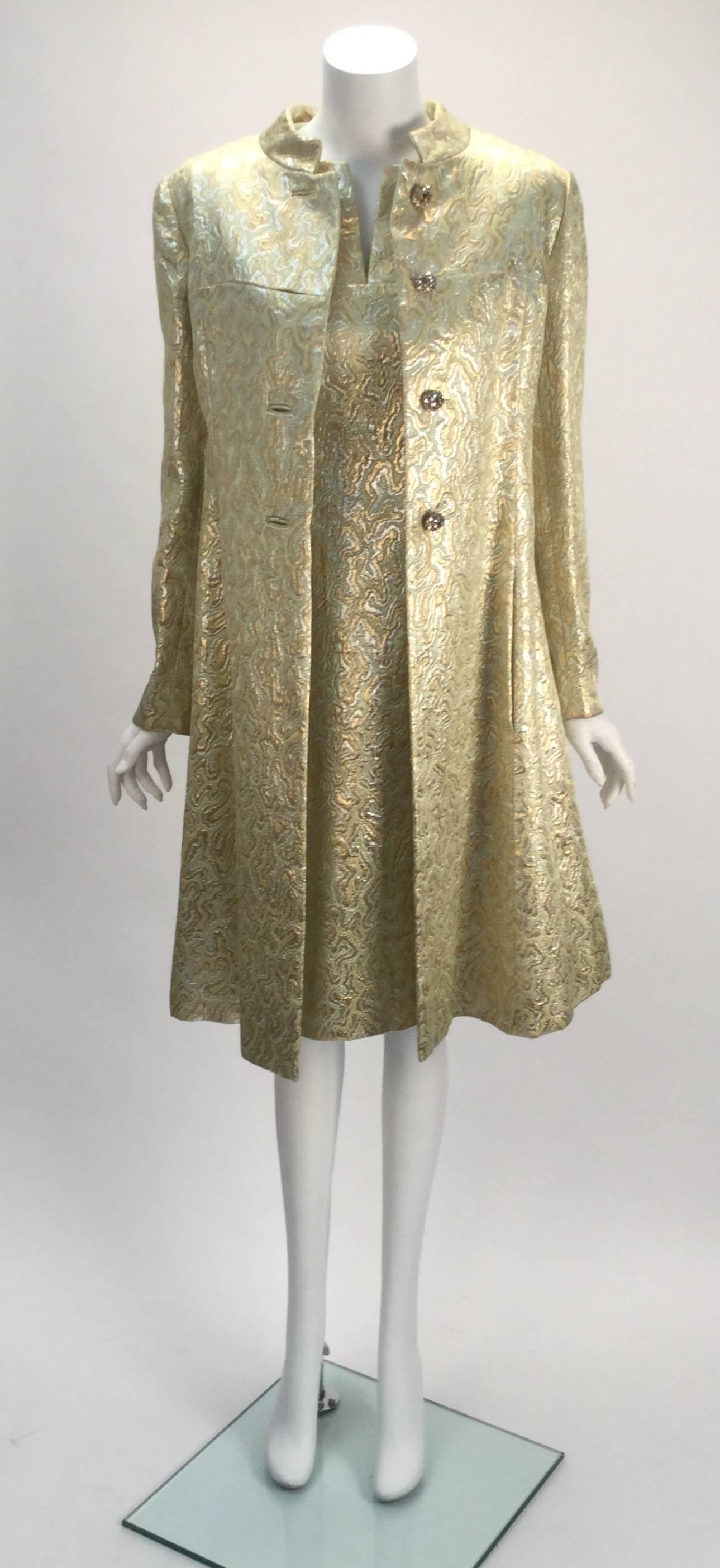 
1960's Malcolm Starr gold and silver metallic colored  three piece evening ensemble. The sleeveless dress has two hidden pockets in front and a zippered back closure. 
The long sleeve jacket has round rhinestone trim buttons for closing at center