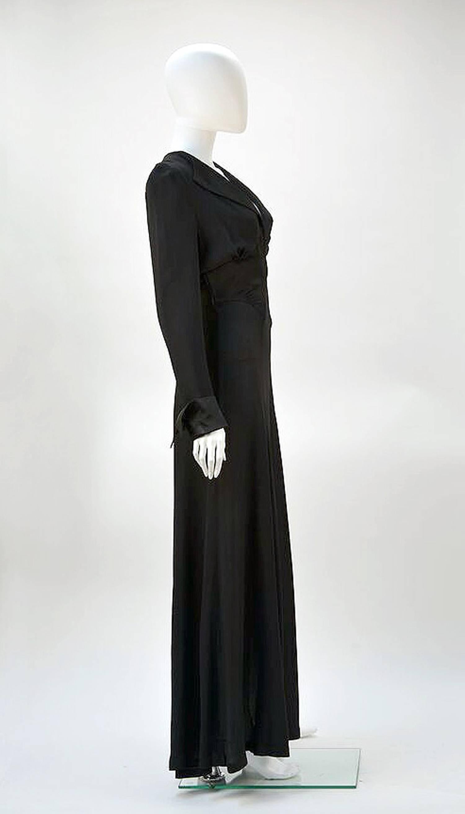 Elegant 1970's Ossie Clark for Radley black moss crepe dress. Dramatic plunging neckline enhances the appeal of this tribute to 1930's design. 
Clark highlights the waistline in both the cut of the dress and the tie at back giving the illusion of