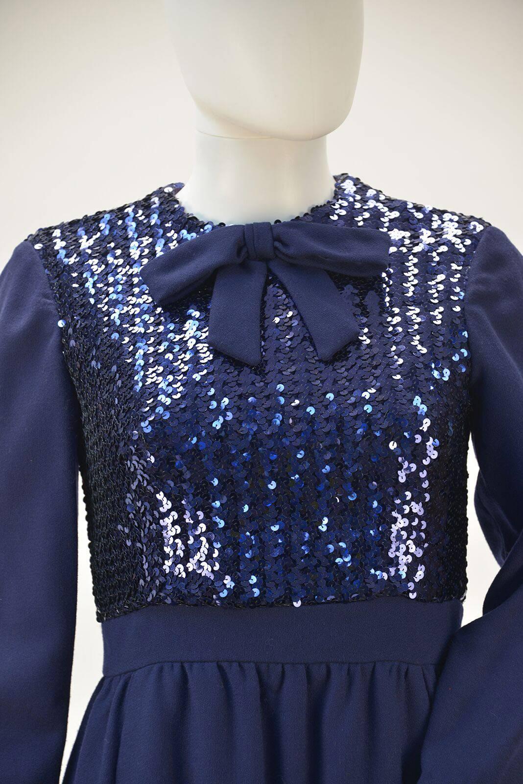 Adorable navy wool dress with sequined bodice! Waist band, skirt, sleeves and bow are all navy wool. Perfect pockets are hidden in the front seams for your essentials. Fully lined bodice. Zipper at center back. Fun, Fun, Fun and warm to