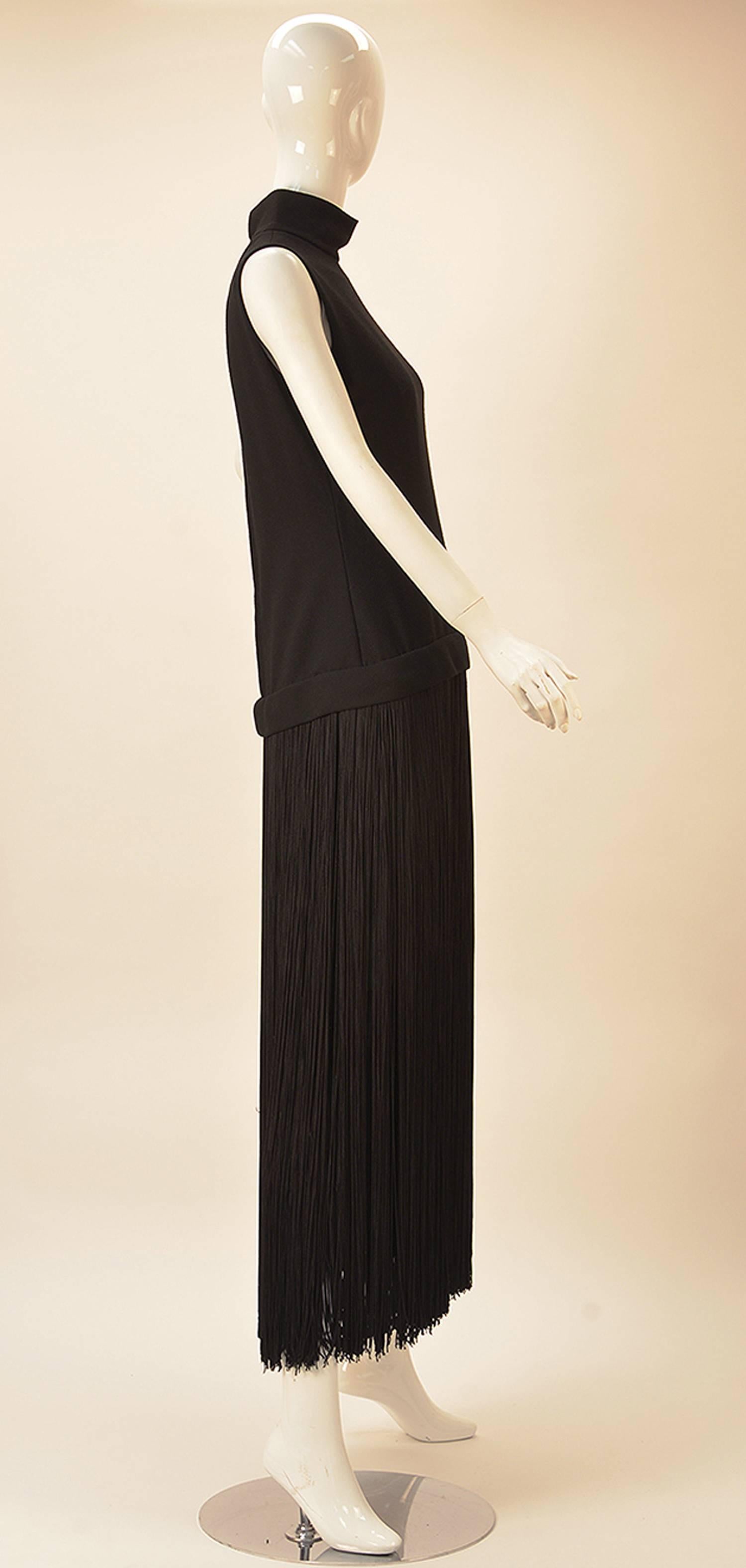 This Adele Simpson 1960's dress is spectacularly layered. The dress is long, with a black fringed under slip. Features stand up collar and drop waist. Zips in back.

This dress fully speaks for itself as depending on height is a maxi dress or of