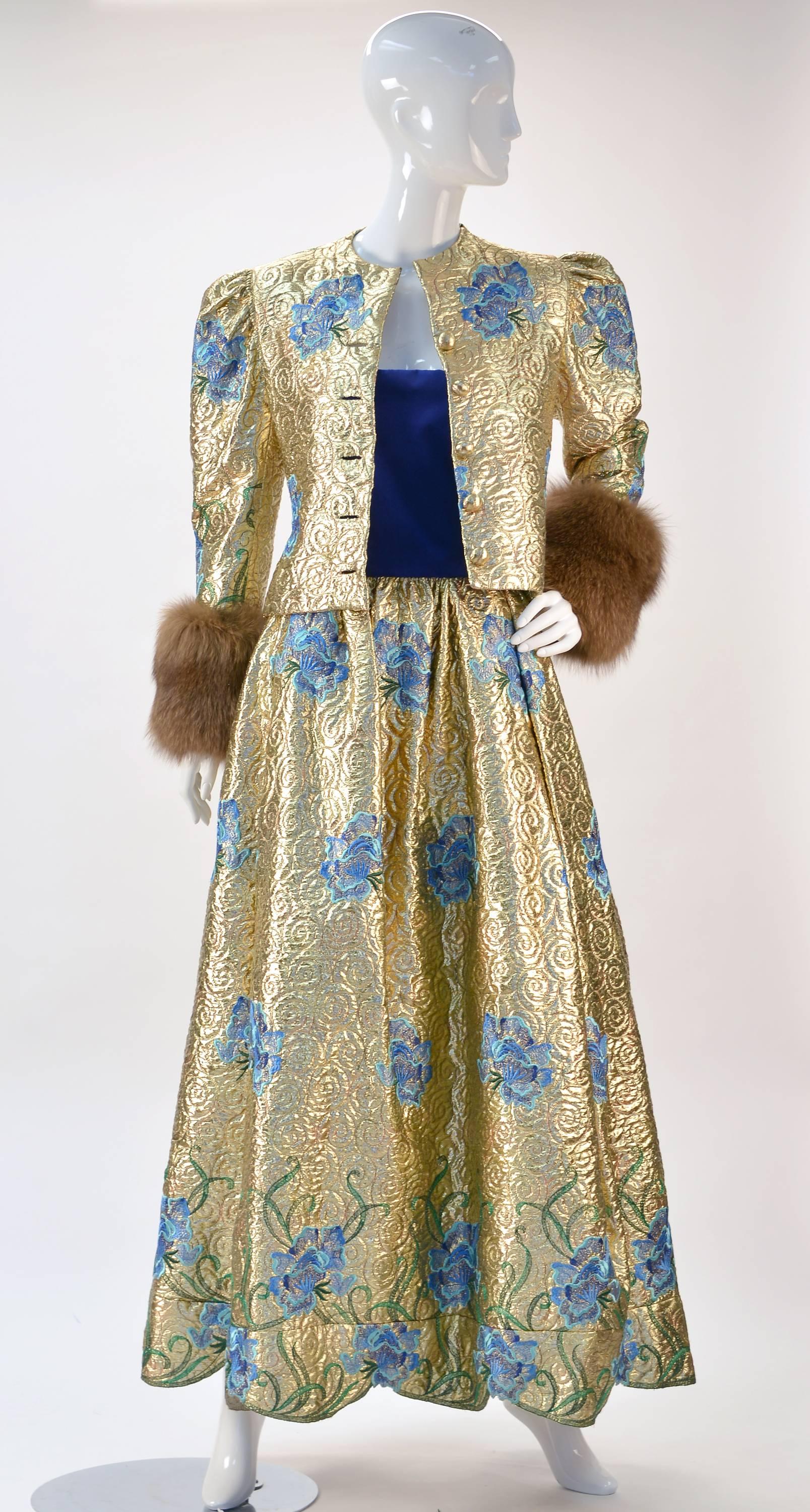 Fabulous Scaasi gold lame dress. Gold Lame is embroidered with gold thread, blue flowers and green vines. Dress bodice is strapless royal blue velvet. Gathered with one pleat in back. Zips at back. The matching jacket buttons at front with gold