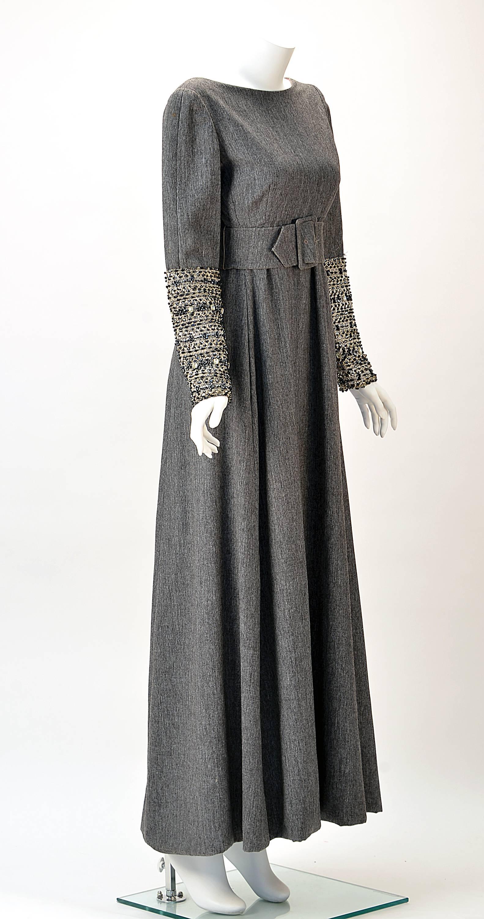 Elegant Malcolm Starr grey wool dress designer by Elinor Simmons. Dress has a low scoop back. Empire waist. Three inch Grey wool belt and buckle. Sleeve  are embellished from elbow down with silver thread and sequins, beads and rhinestones.