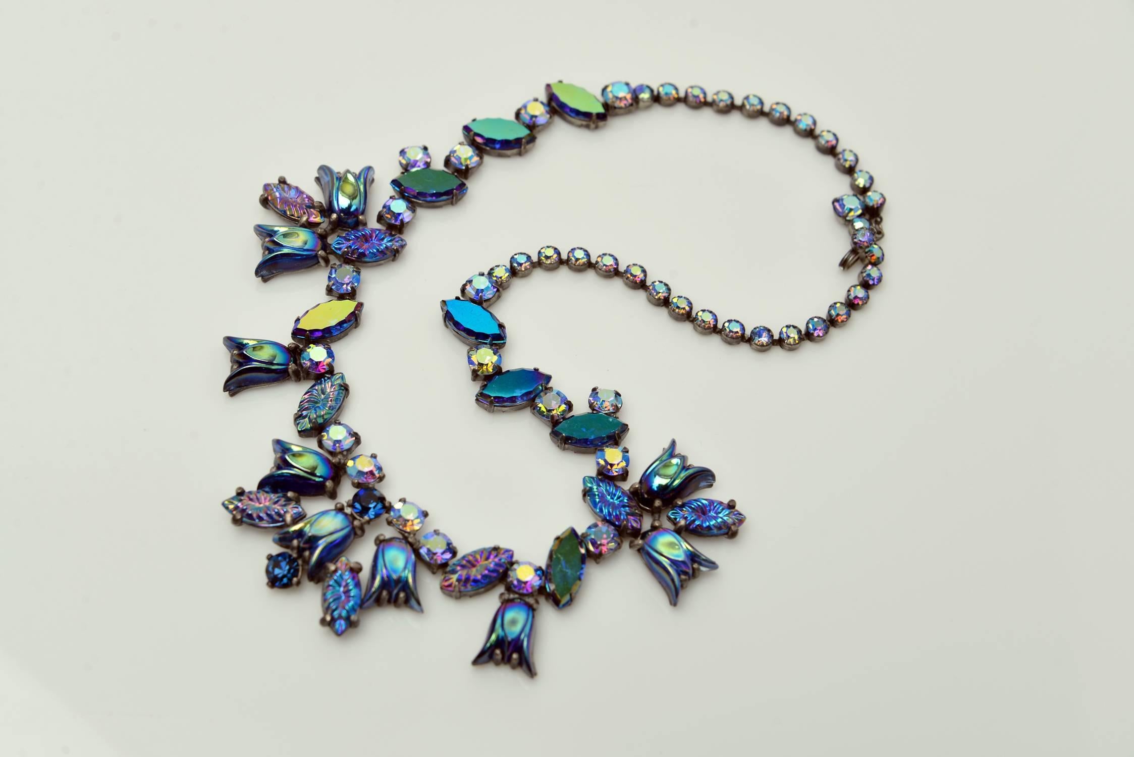 Beautiful vintage art glass and rhinestone necklace by Elsa Schiaparelli. The necklace features amazing iridescent icy blue “lava rock” and iridescent art glass stones, beautiful iridescent flashed carnival-glass like cabochons, and dazzling light