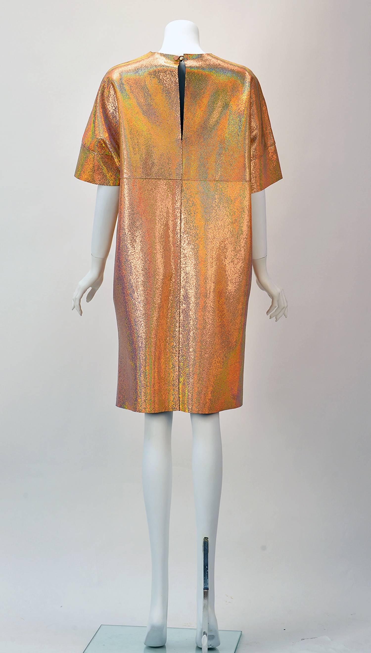 This Vera Pelle/Leather shift dress aesthetically stands alone; both dramatic and fun!
The dress of Hologram Vera Pelle/Leather is thoughtfully constructed with overlapping seams.  The fabric glimmers a pinky/peach/purple with silver and gold.