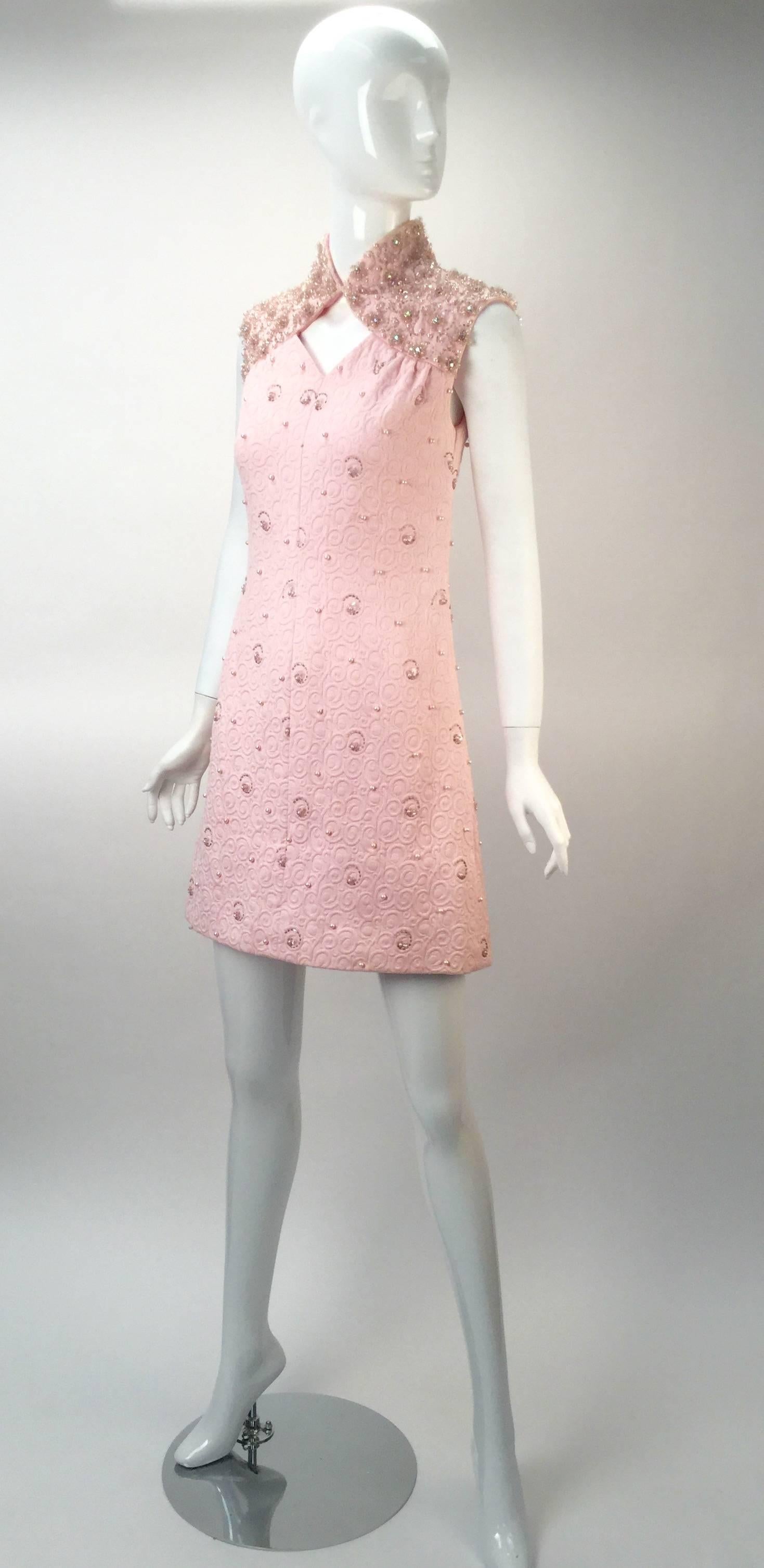 Wonderful spring mini dress by Canadian fashion designer Ruth Dukas.  The dress is a pink cotton jacquard with great bead work. 

Heavily sequined and beaded collar and shoulders. Diamond cut-out on breast bone. Dress is fully lined. Zipper center