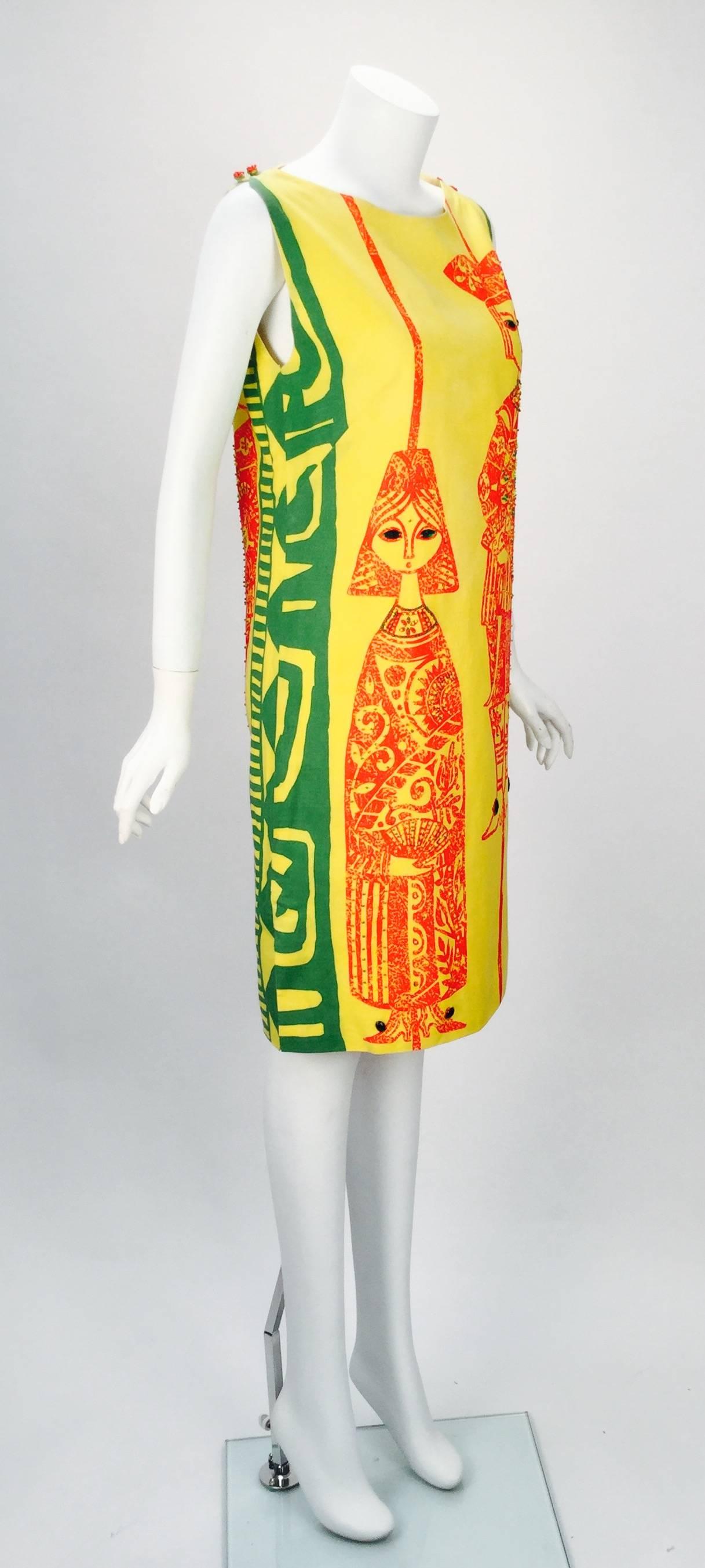 Fantastic early 1970's Vintage Mills yellow printed sack dress.  Both the front and back have two Castillo people adorned with red and green beading along the printed  pattern. Eight emerald rhinestones  (per side of dress) adorn the eyes and shoe