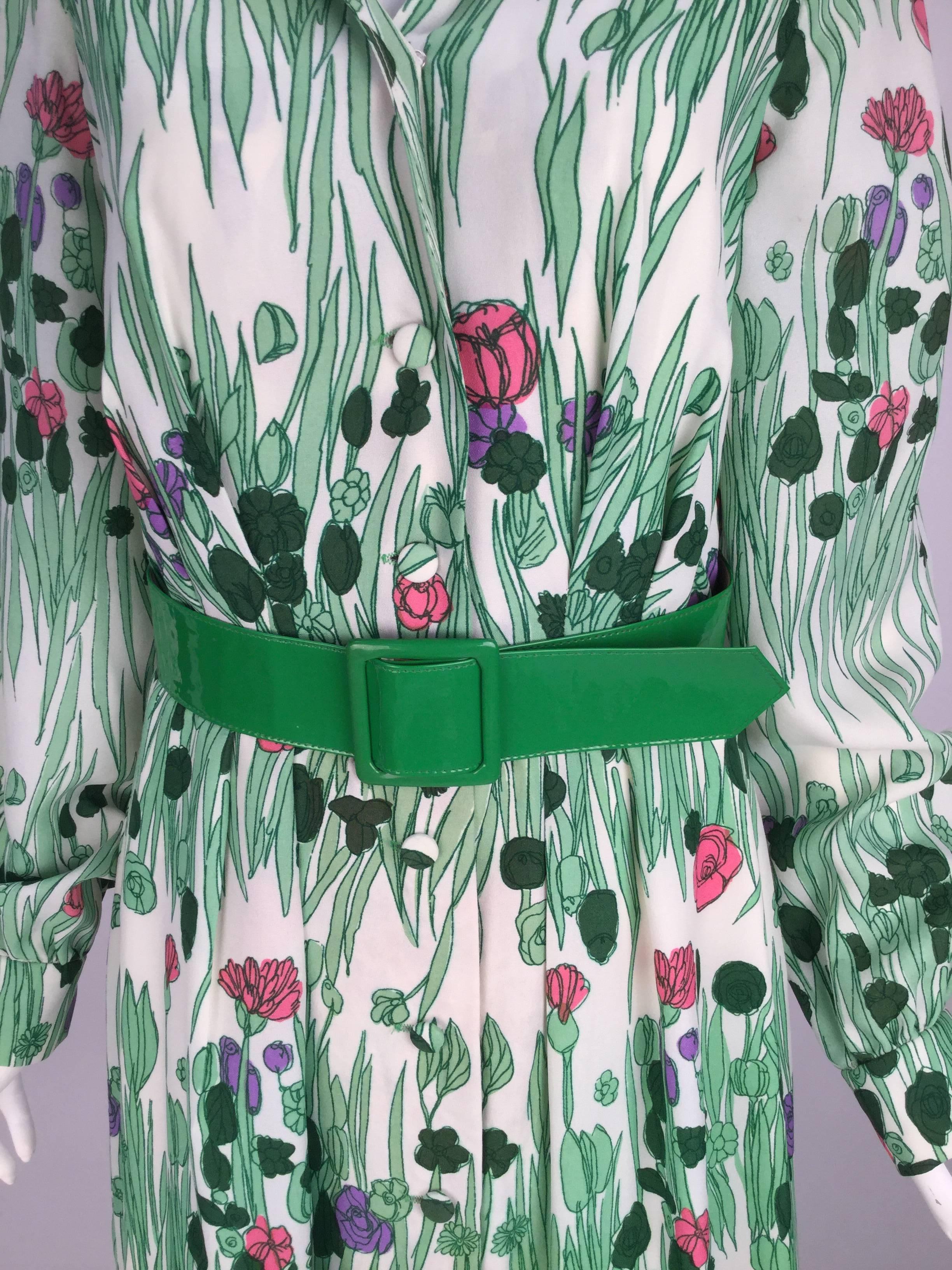 
Vintage 1970's Estevez maxi dress under his Eva Gabor look line.  
Dress has an amazing green grass print with flowers. 
Over sized collar with button down front. Sleeves have one button on each cuff. Matching green vinyl belt. 
Gathered skirt.