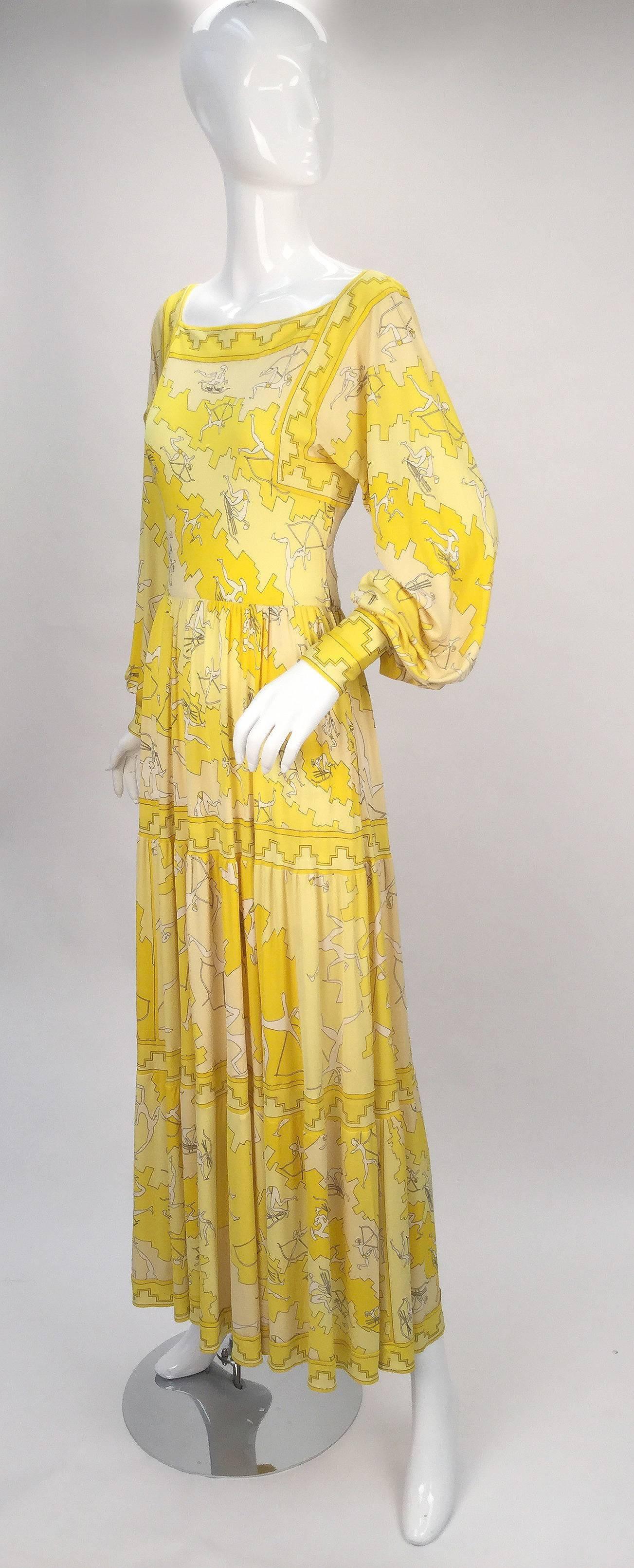 Ethereal 1970's Pucci Yellow Silk Knit print.  The Olympic inspired print boasts abstract sportsmen/women in various stages of sport. The archers' bodies are signed Emilio. 

Gown has billowy bishop sleeves with cuffs that button at the wrist, and