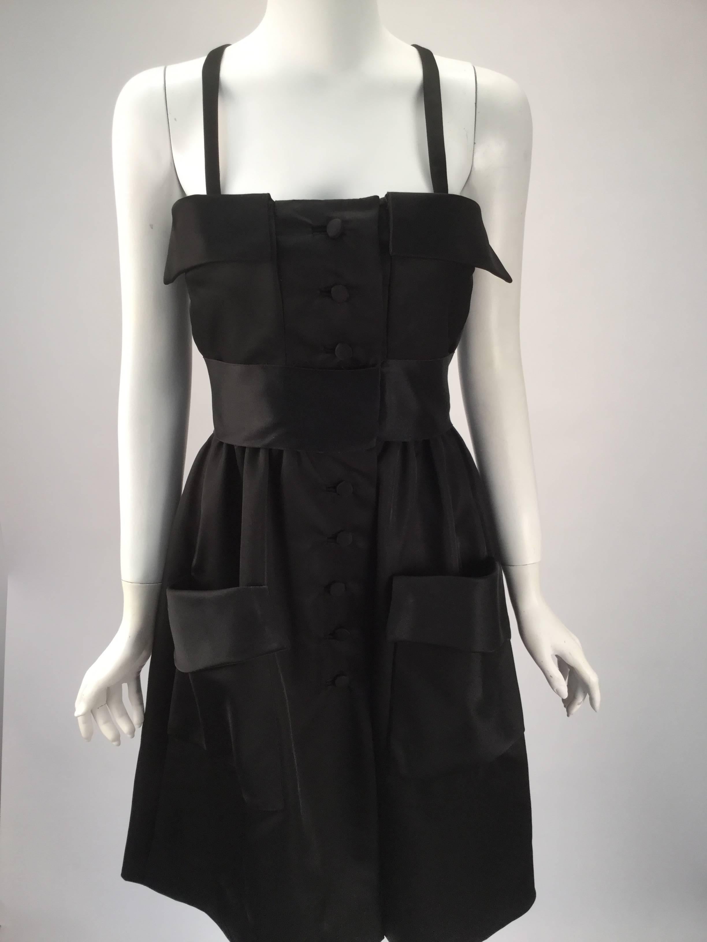 Gorgeous and uber-comfortable black satin dress with two large pockets center front. Black satin sash sits as an empire waist. The front of the dress has two fold-over flaps on the top of the dress. Eight buttons run from top until mid thigh.