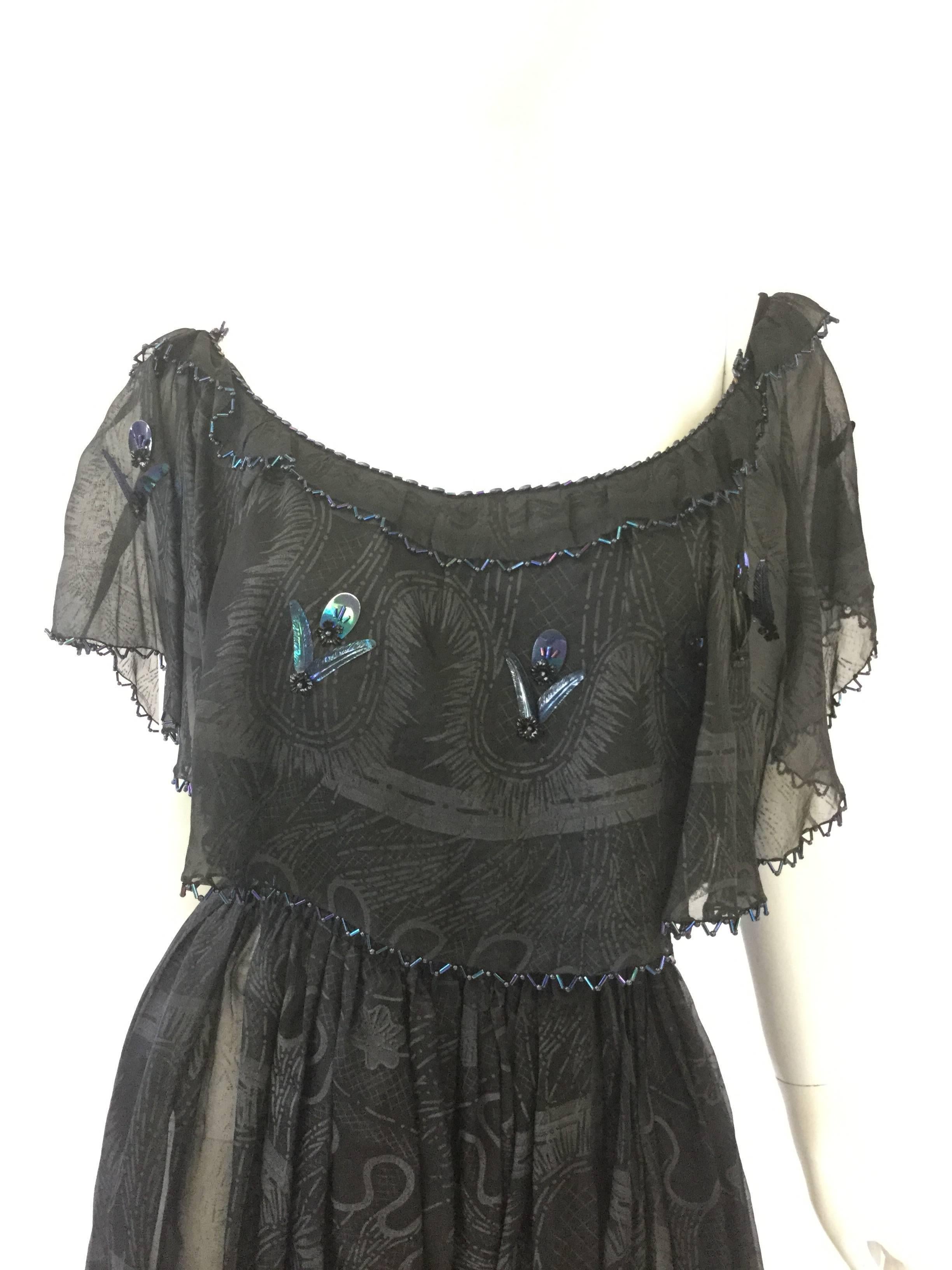This gorgeous black silk illusion dress features a large hand painted hand stenciled abstract organic mandala-like print in grey and black. The sleeveless dress has a caplet collar with carnival glass bead trim and has elastic on the shoulder. The