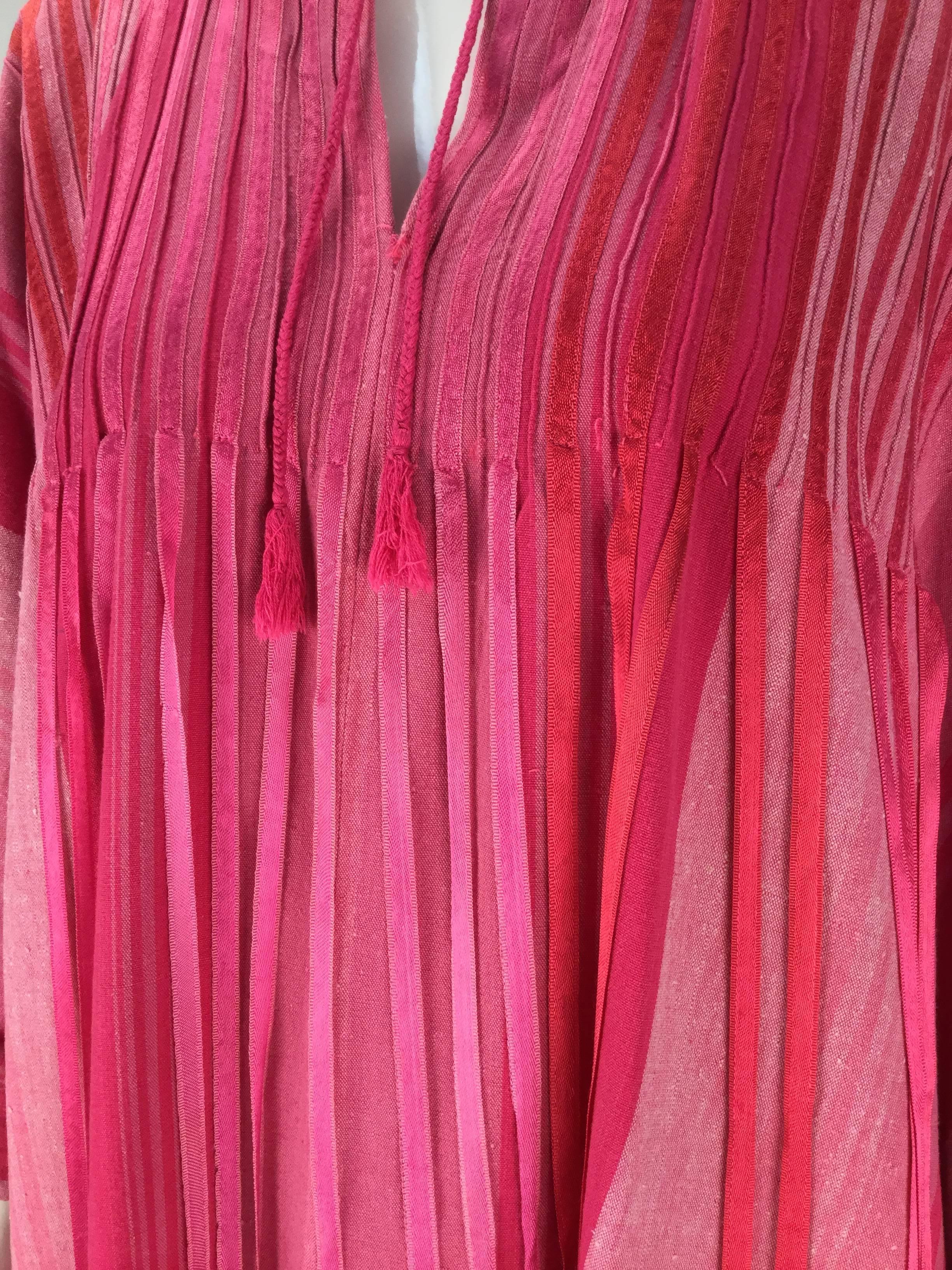 Stunning 1970s multi pink striped kaftan with ribbon trim by famed Mexican designer - Josefa. 100% cotton. It is made of brightly striped cotton in shades of pink with strips of satin ribbon that are stitched down to bust and then hang freely in a