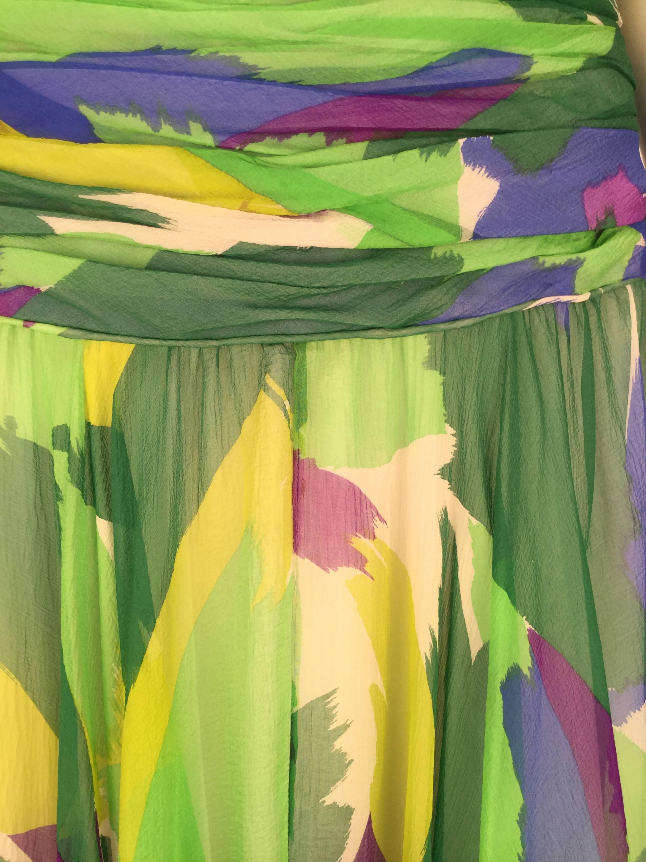 Gorgeous 1990's dress printed with an abstract multicolored design comprised of shades of green, blue, purple, and yellow. The bodice is beautifully gathered along the sides leading into a full skirt beginning with a dropped waist. The shoulders are