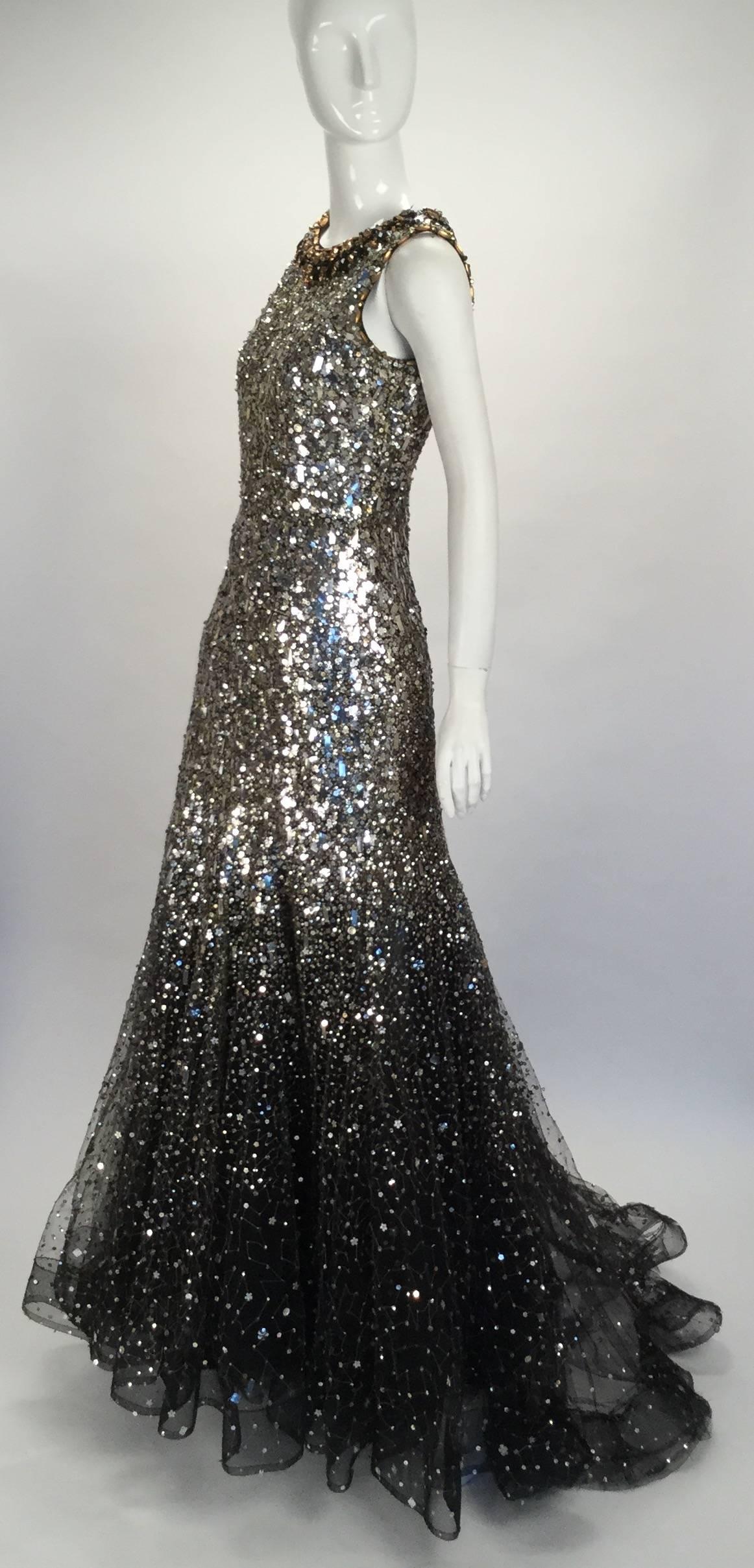 Gorgeous sequined Oscar de la Renta formal evening gown. Beautiful gold beading over mesh follows the neckline with accents of black and a rich gold color. The dress is covered in silver and gold sequins in assorted shapes and sizes. It fits closely