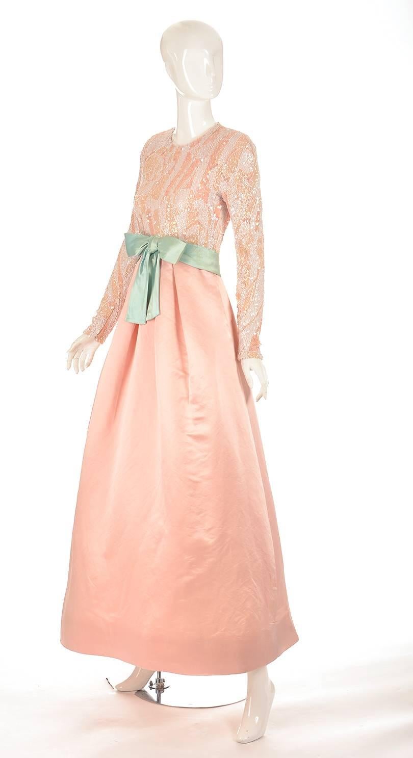 1960's Arnold Scaasi evening dress. This gorgeous blush pink silk evening dress has a pink over white bodice. White and peach colored sequins and beads fully decorate the bodice of the dress, and continue down the full length of the sleeve. The