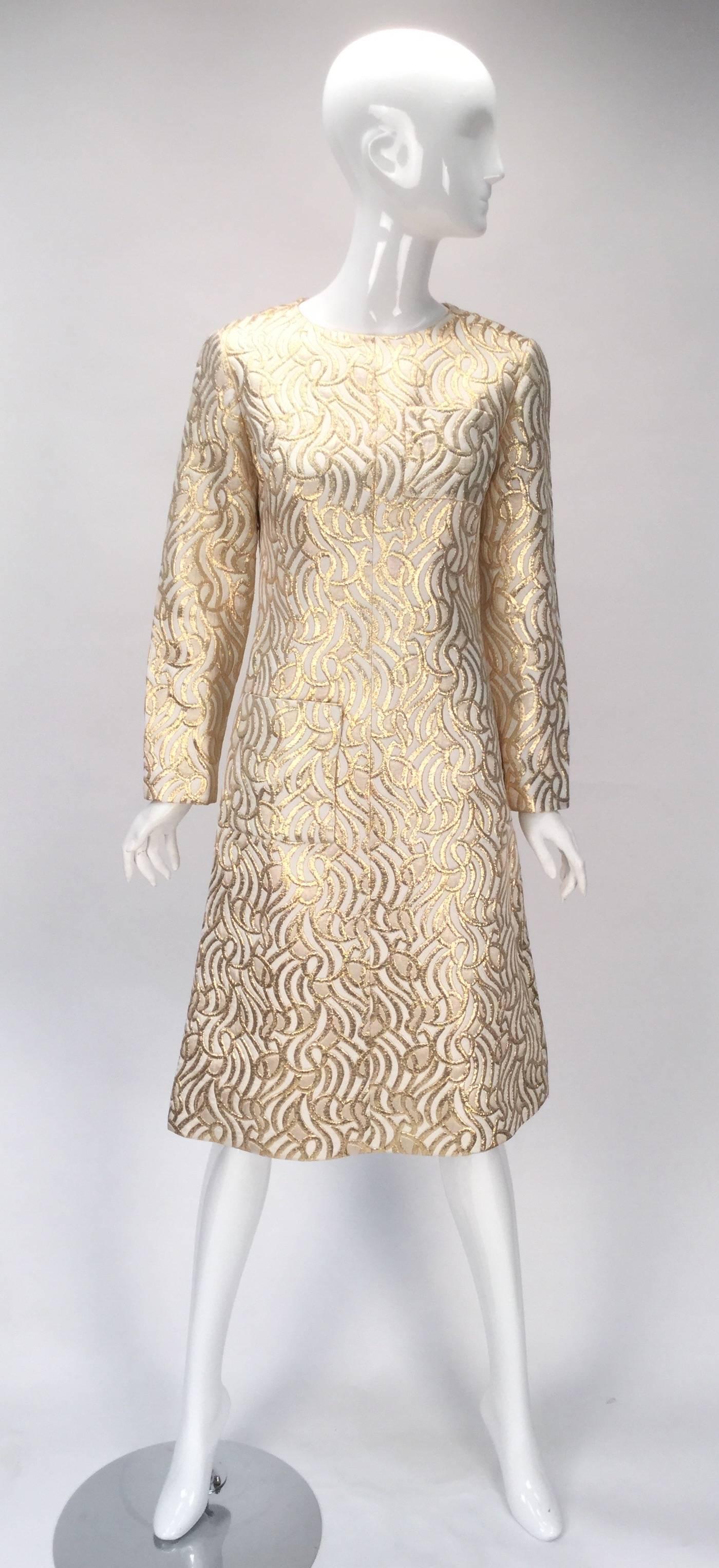 Vintage 1960s dress. This gorgeous cream and gold metallic brocade dress features an abstract organic pattern with undulating waves, swirls, curves, and curls. The dress has a center front seam, pocket at bust and hip, and scoop neckline. The dress