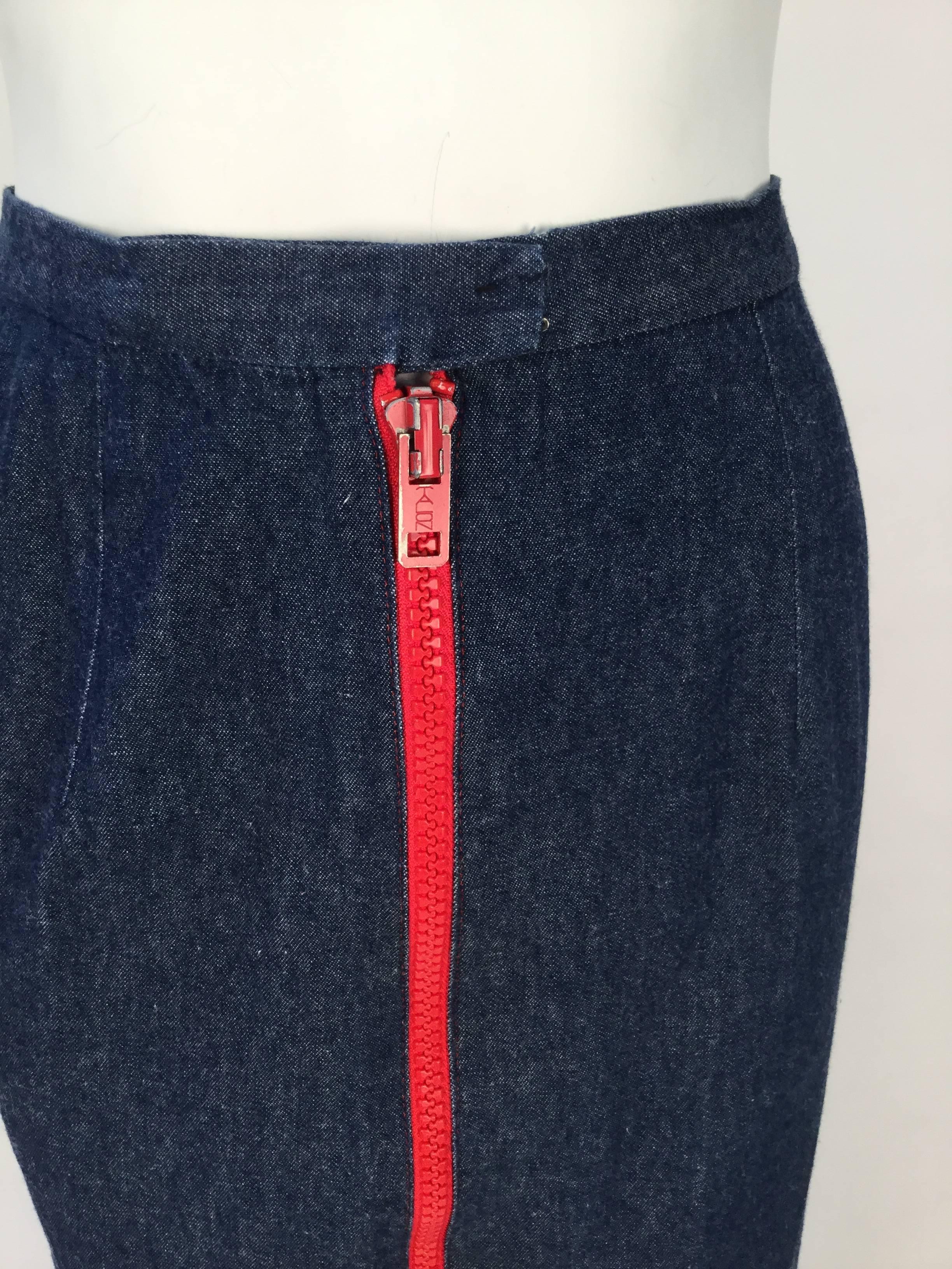 1970's faded dark wash denim midi skirt from Geoffrey Beene's 'The Beene Bag' line. Center front hook and eye closure. There is a large red metal and plastic two-way zipper that zips down center front. Red top stitching at bottom hem and by the