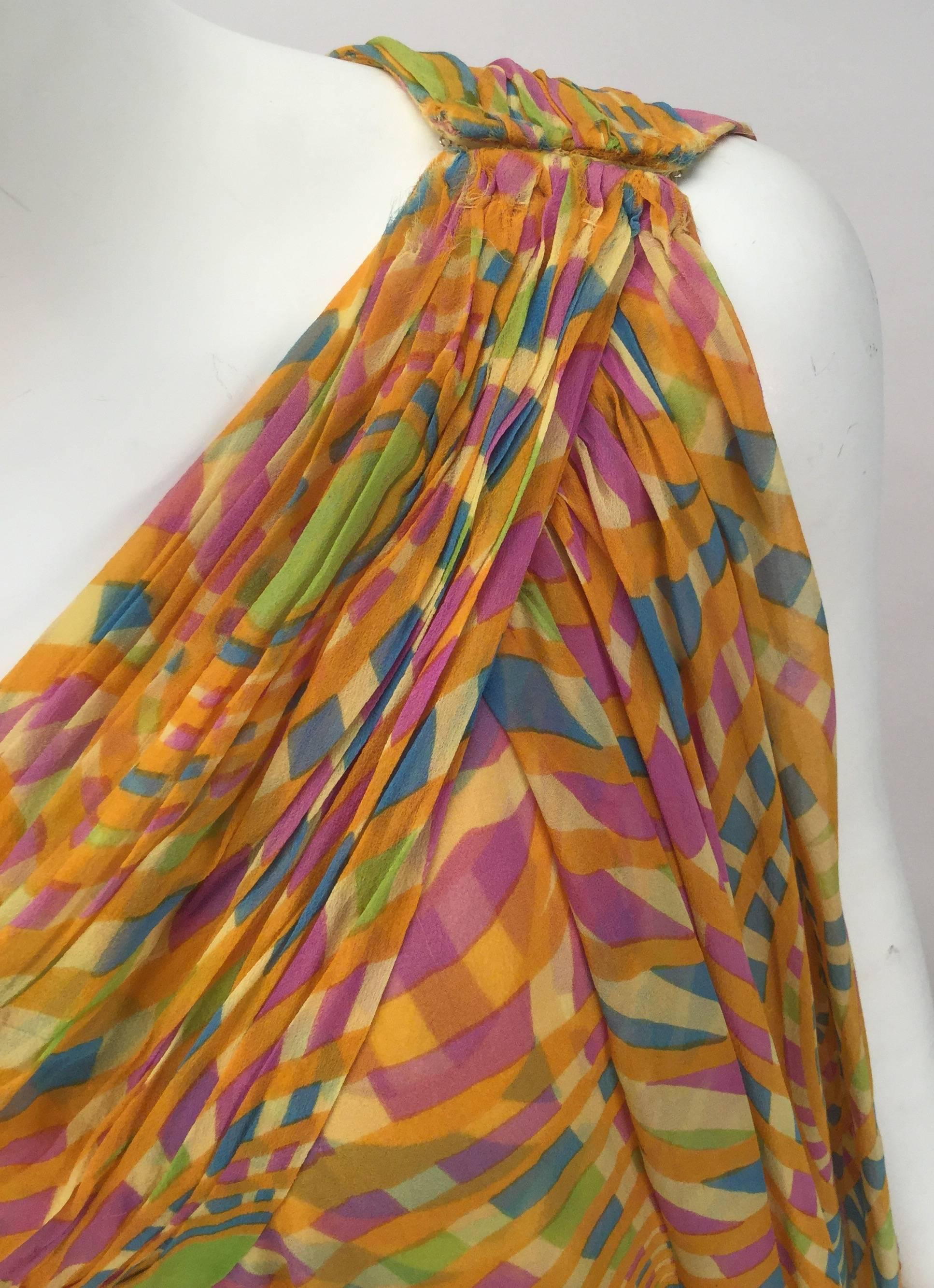 Sheer and flowing 1970s dress by Malcolm Starr.  Perfect for summer or any time of year resort or lounge wear. Fabric is yellow with green, pink and blue spiral prints on sheer silk Crepe de Chine. One shoulder dress with five hook and eye closures.
