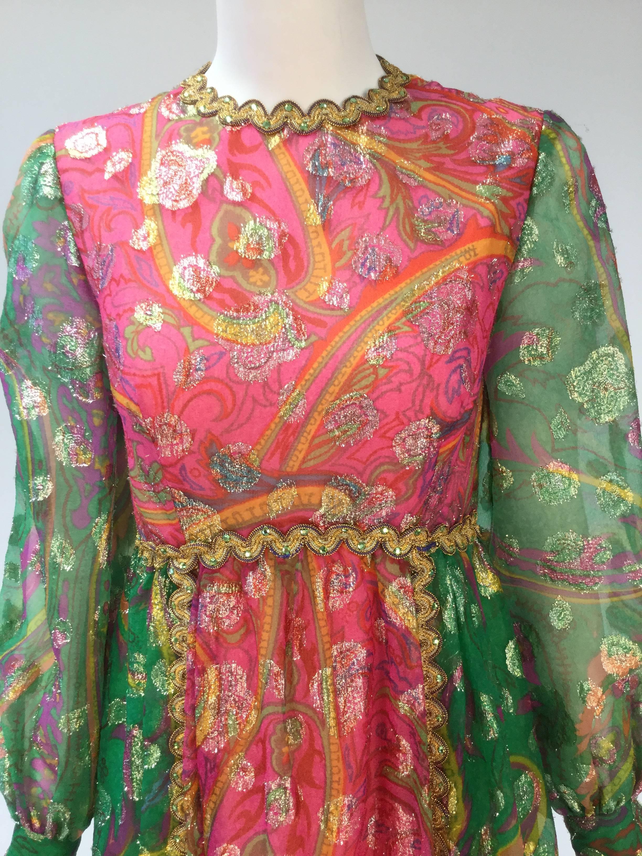 
Bold and vibrant statement piece from the Gino Charles label.  Pink and green dress is trimmed in gold around the neckline, sleeves, waistline and down the skirt of dress. The gorgeous trim is adorned with green rhinestones. Metallic threading