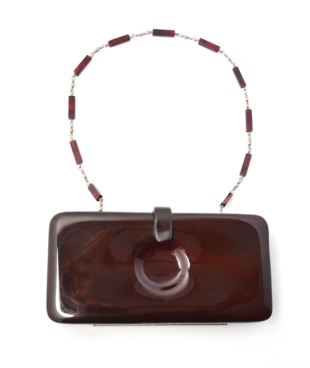 Fantastic 1970's Italian dark brown Lucite clutch with a circle indent in the center front and back. Beaded lucite and silver chain strap. Clutch features silver hardware and brown leather interior lining.  Can be used as clutch or a shoulder bag.