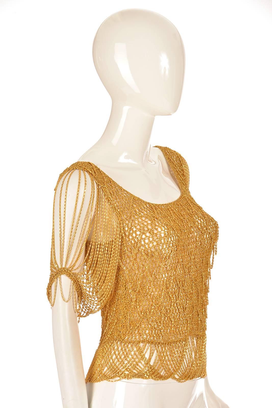 

A simply fantastic top! This intricately woven gold-tone Chain and knit sweater has light chains incorporated into the diamond scallop weave. The sleeves of the top are delicate festooned chains, and the top features a scoop neck. The top slips