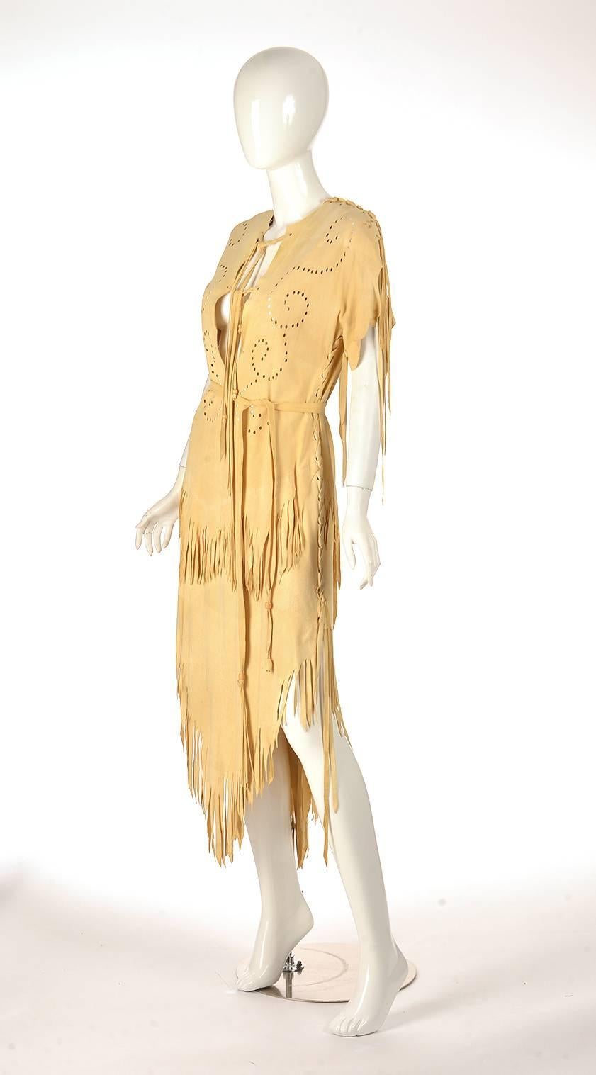 
Native American leather dress with double layer fringed bottom. Dye cut swirl design on top half of dress. Dress features straps of leather, finished with beading. Sleeves are threaded together with leather. Dress slips overhead. Can be worn, used