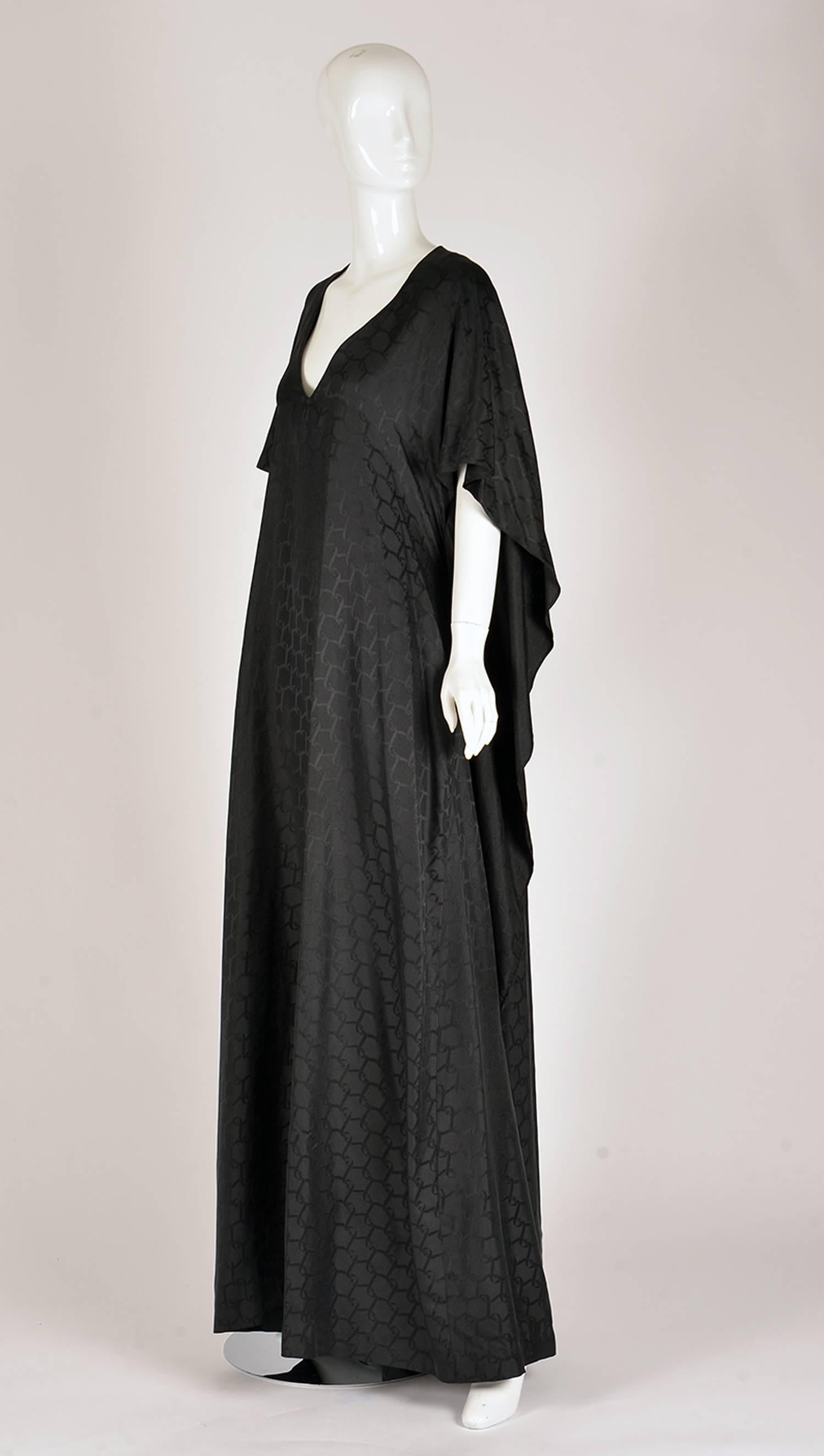This Roberta di Camerino 1978 black silk caftan is magnificent! With a wrap waist band for the skirt underneath (back) the top cape-like piece is allowed to flow behind. The back is open underneath the cape. This dress has a V neck as the main