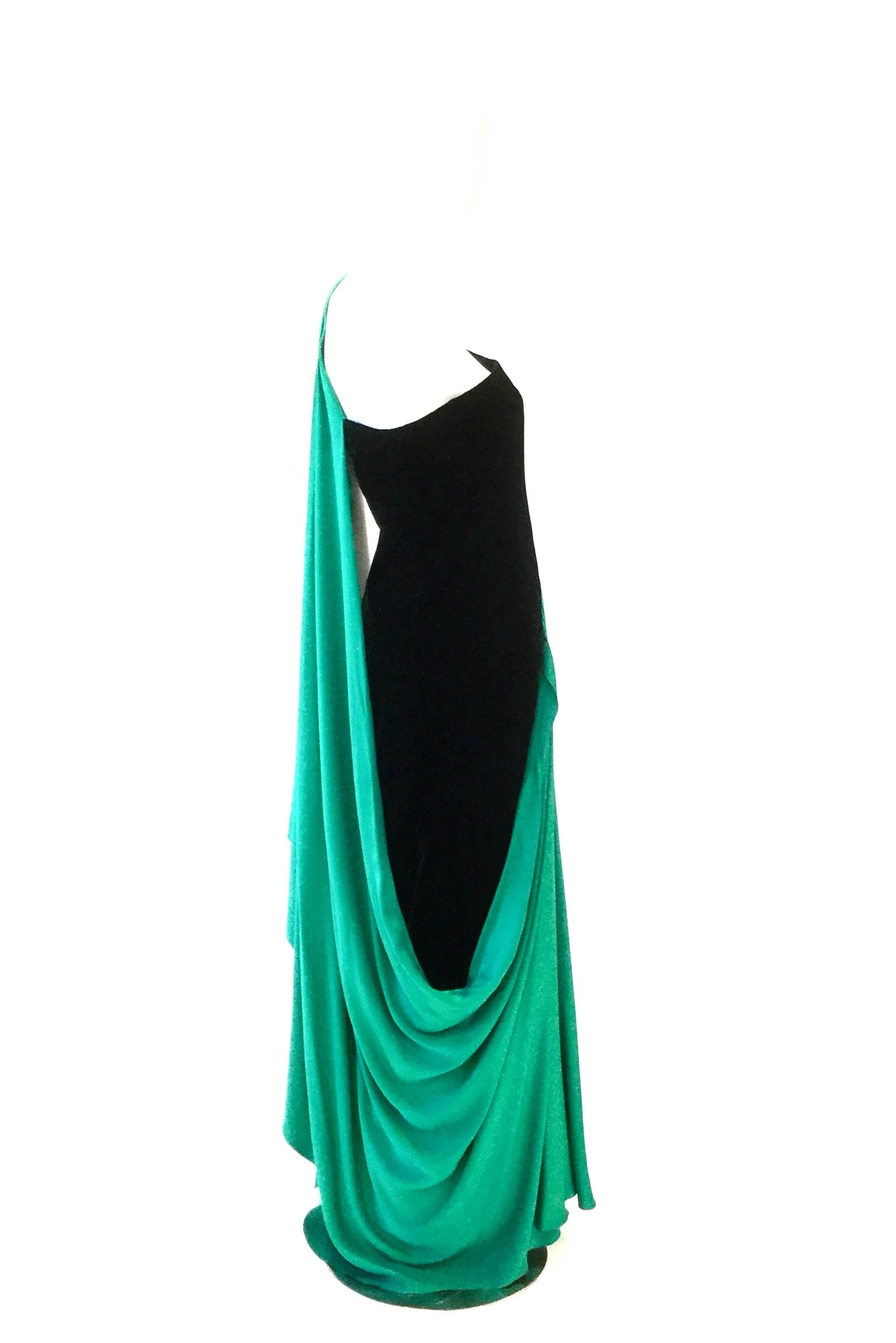 Exquisite French designed gown by Jaqueline de Ribes. This body of the gown is made sumptuous black velvet, accented by a striking emerald green fine silk shoulder cape drape. The one-shoulder drape-strap has elegant pleats at the top, causing the