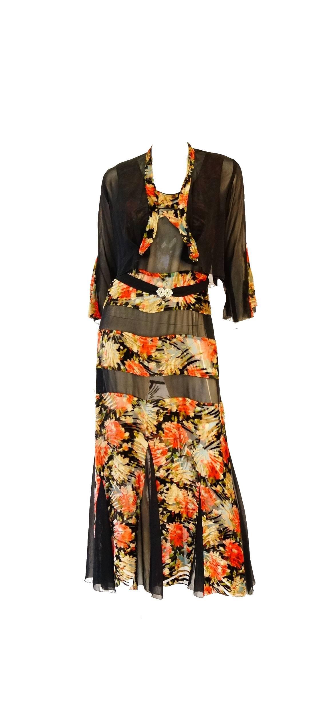 Romantic vintage maxi dress with matching bolero. This ankle length dress features alternating panels of floral rose burn out velvet in fall colors, including red, gold, blue, pink, and green, and black. The sleeveless dress has a godet skirt with