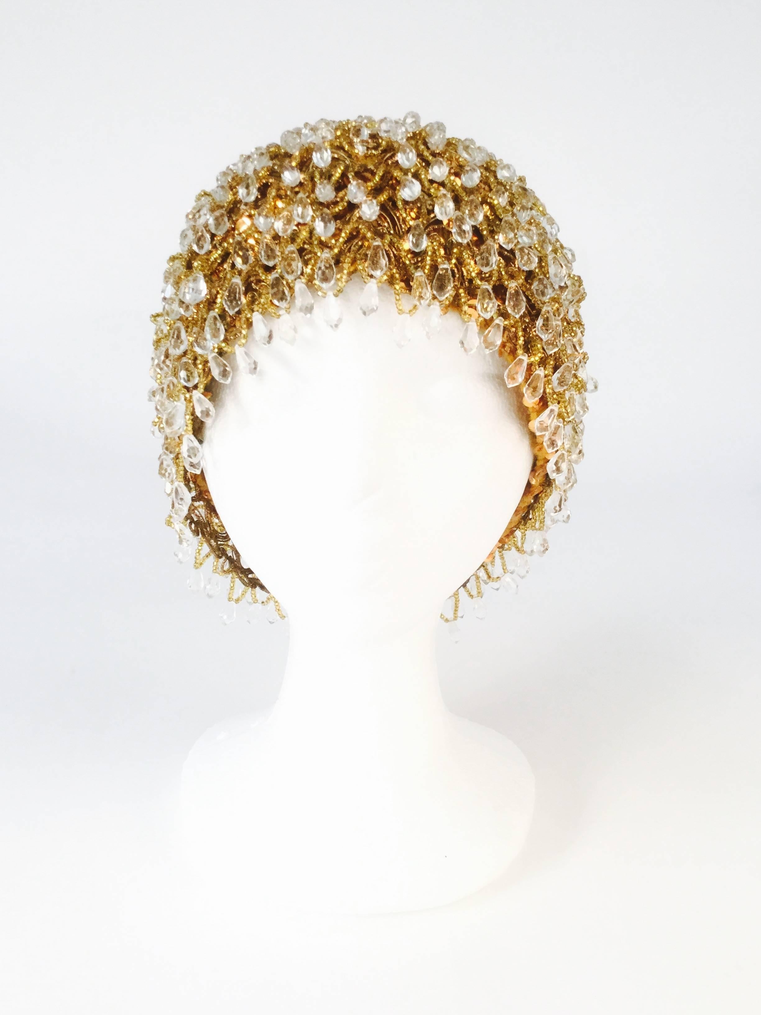 
Stunning vintage toque by Madcaps Paris-New York for Sakowitz. This luminous hat features gold seed beads punctuated by faceted teardrop shaped beads, arranged in a scalloped pattern over copper sequins. The strings of gold seed beads and dangling