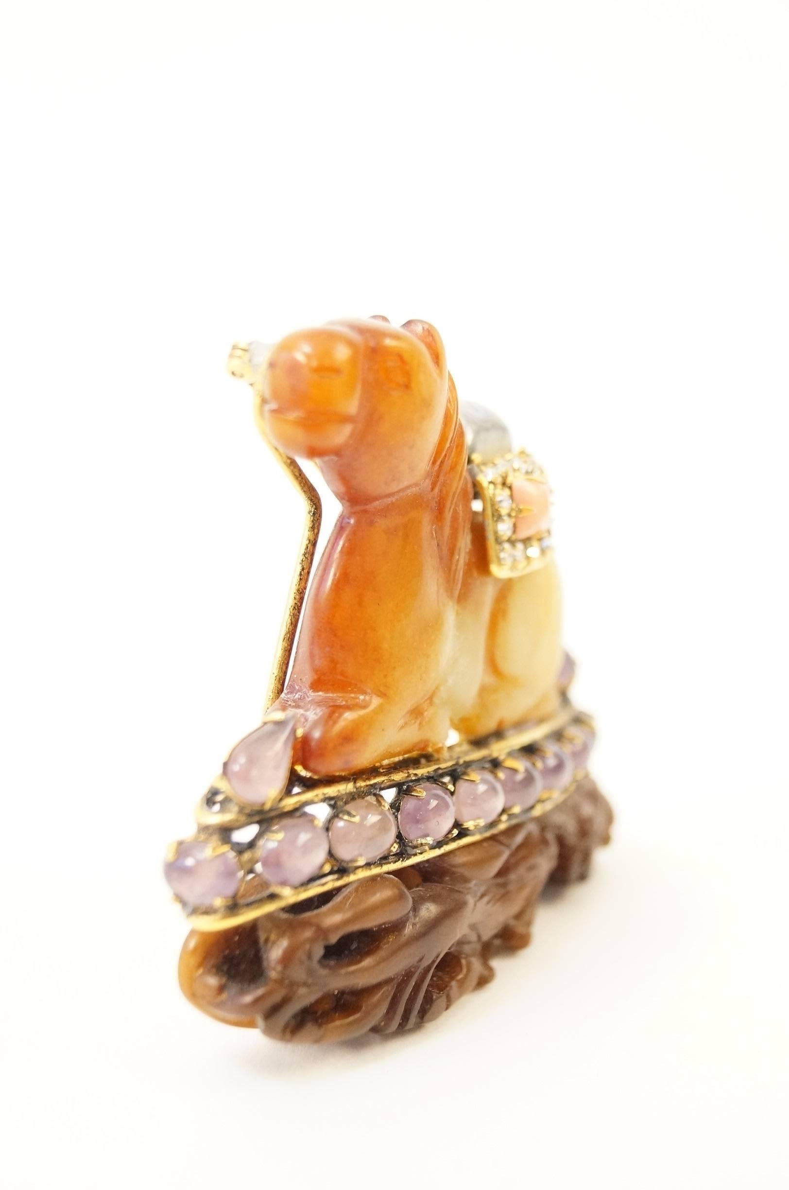 
This brooch by Iradj Moini is a tremendously beautiful piece of art. The brooch is composed of a antique agate piece formed into a horse siting on top of a soapstone dragon. The horse and dragon are separated by a row of oval amethyst cabochons.