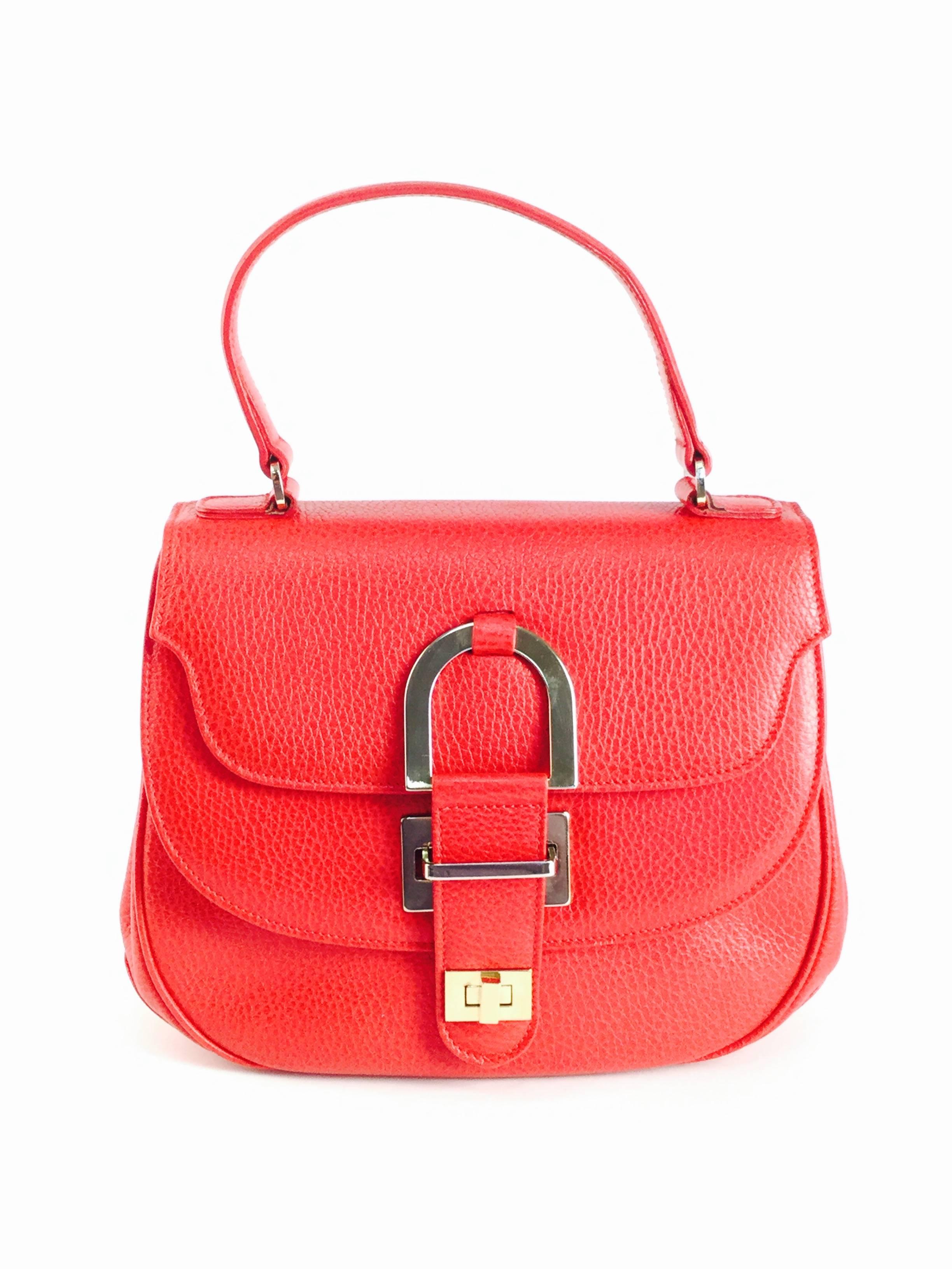 
Gorgeous double flap bag by Oscar de la Renta! This top grain red leather bag has a top handle and features two separate compartments, each covered by a curved edge flap; the topmost flap has a pointed beveled cut. Both compartments are lined in